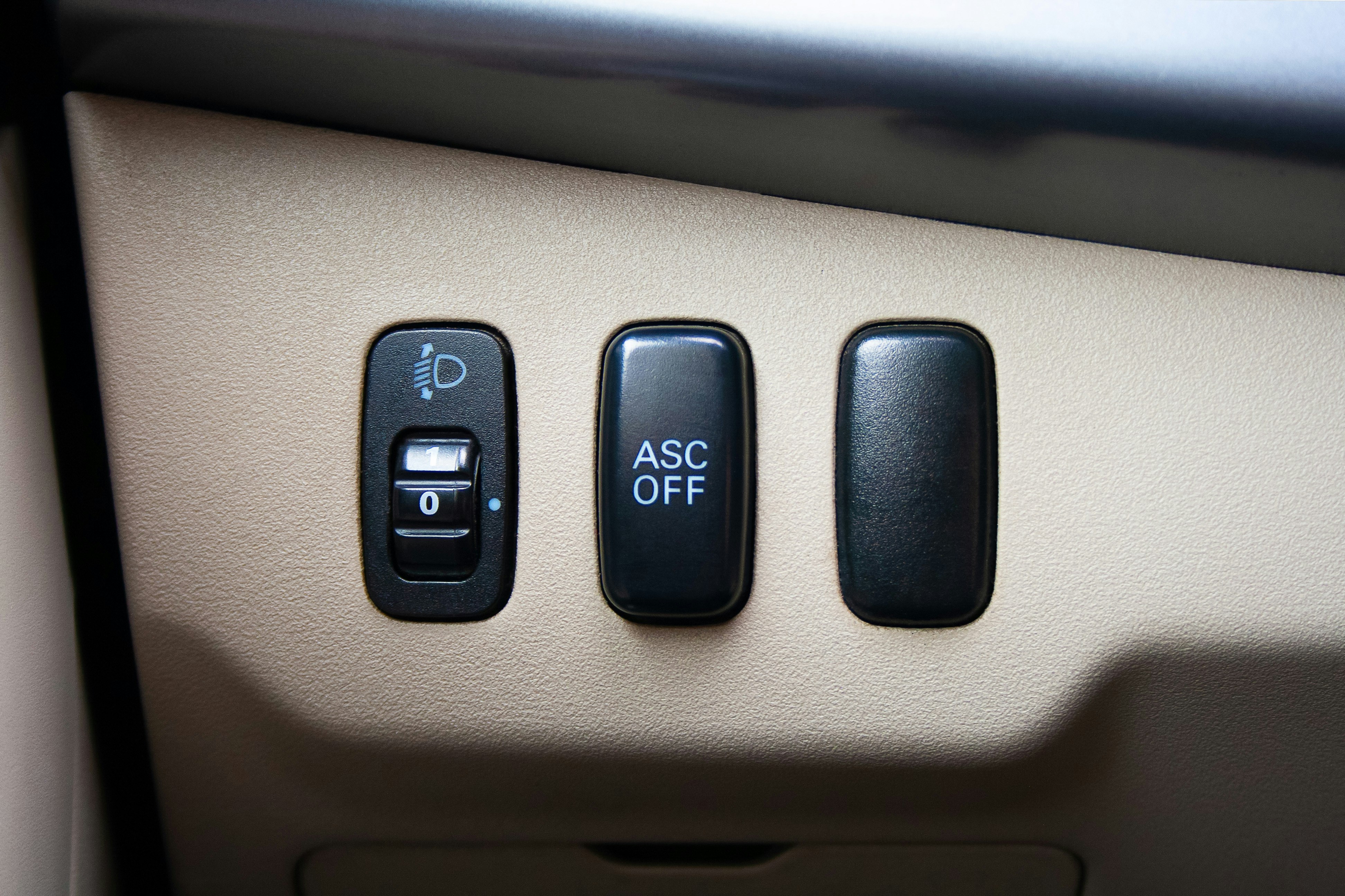 A headlight level adjustment dial and an ASC OFF button on a car dashboard