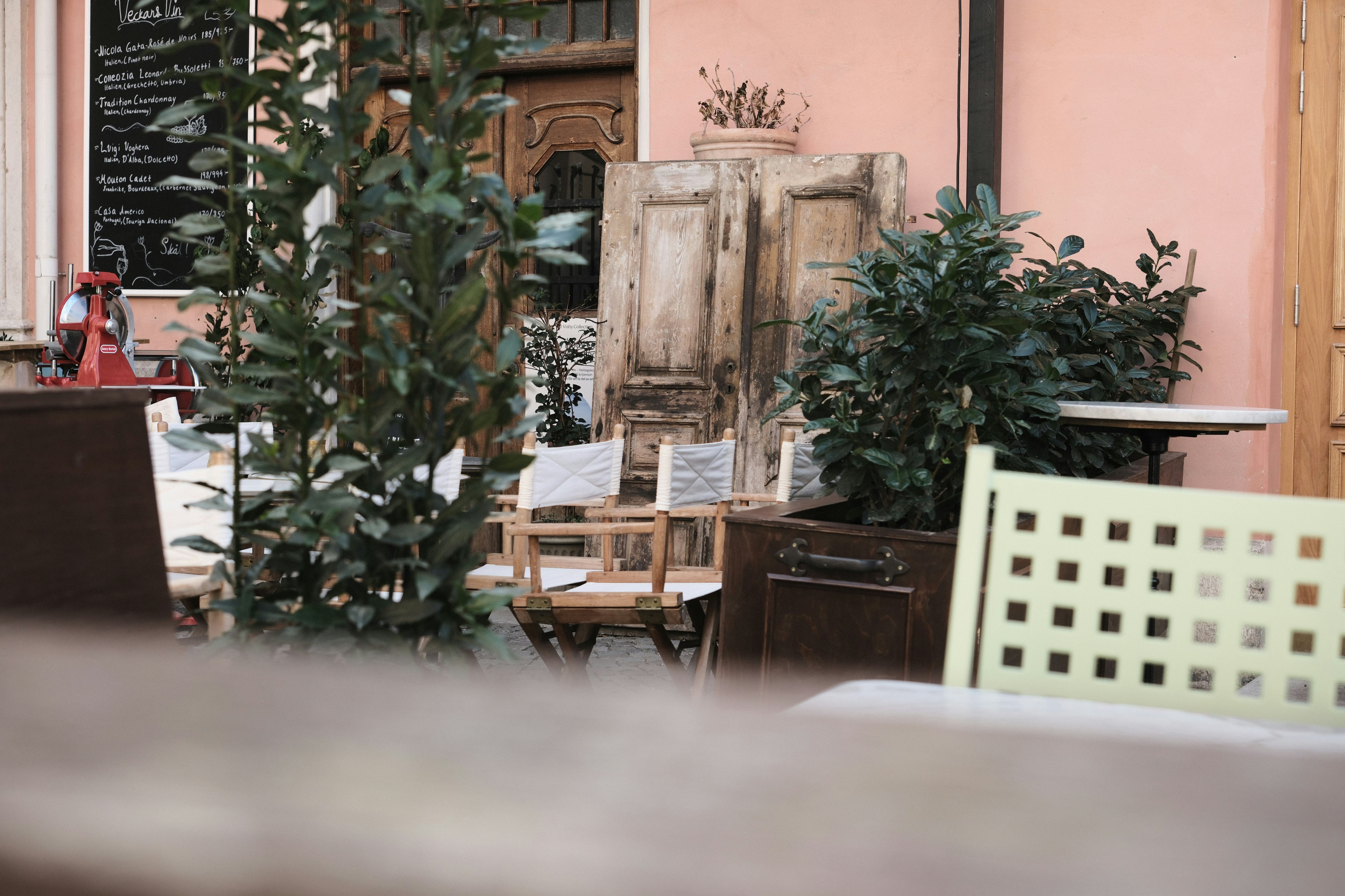 Folding chairs and potted plants on a patio outside a pink building