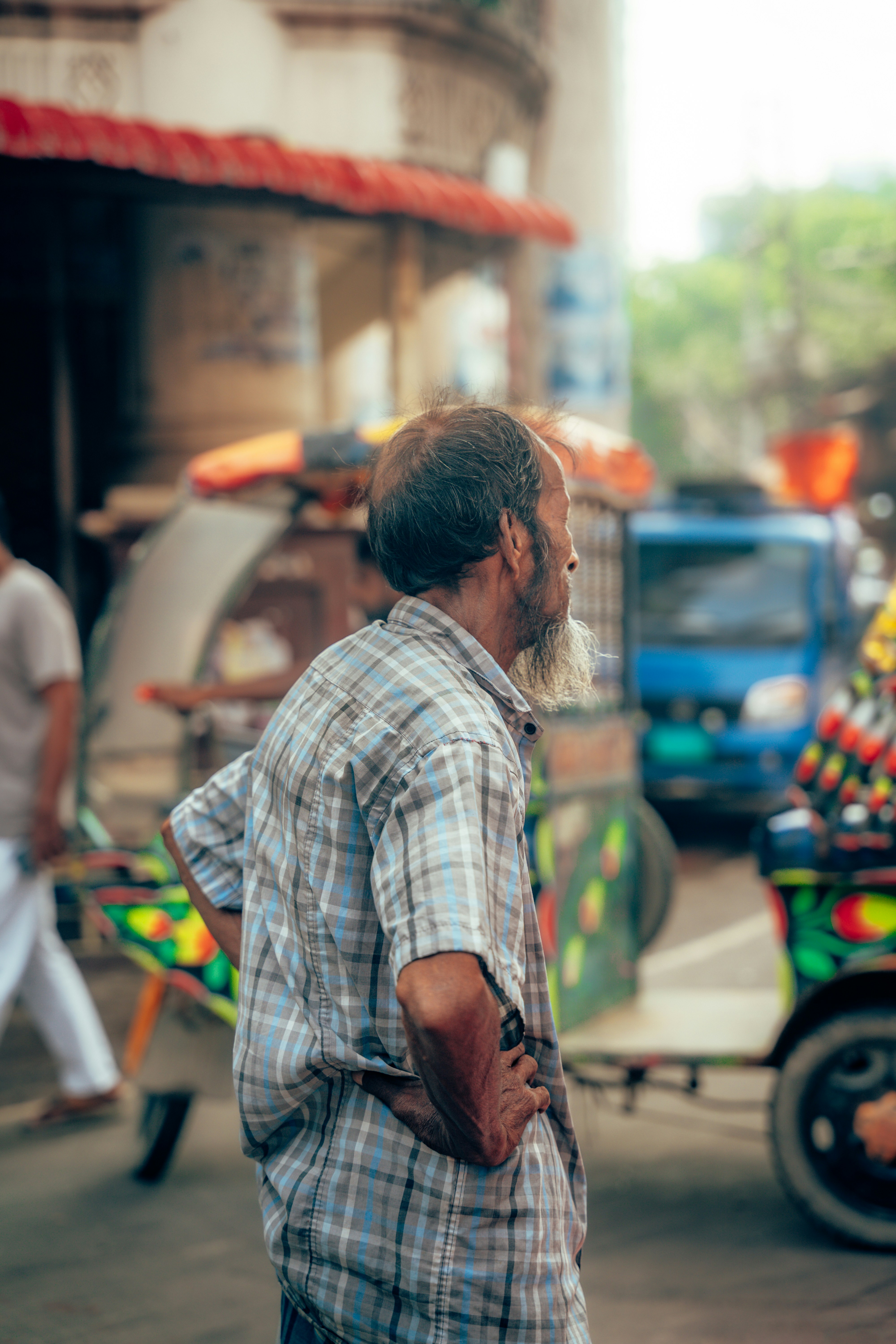 An older man with a beard in a plaid shirt on a busy street