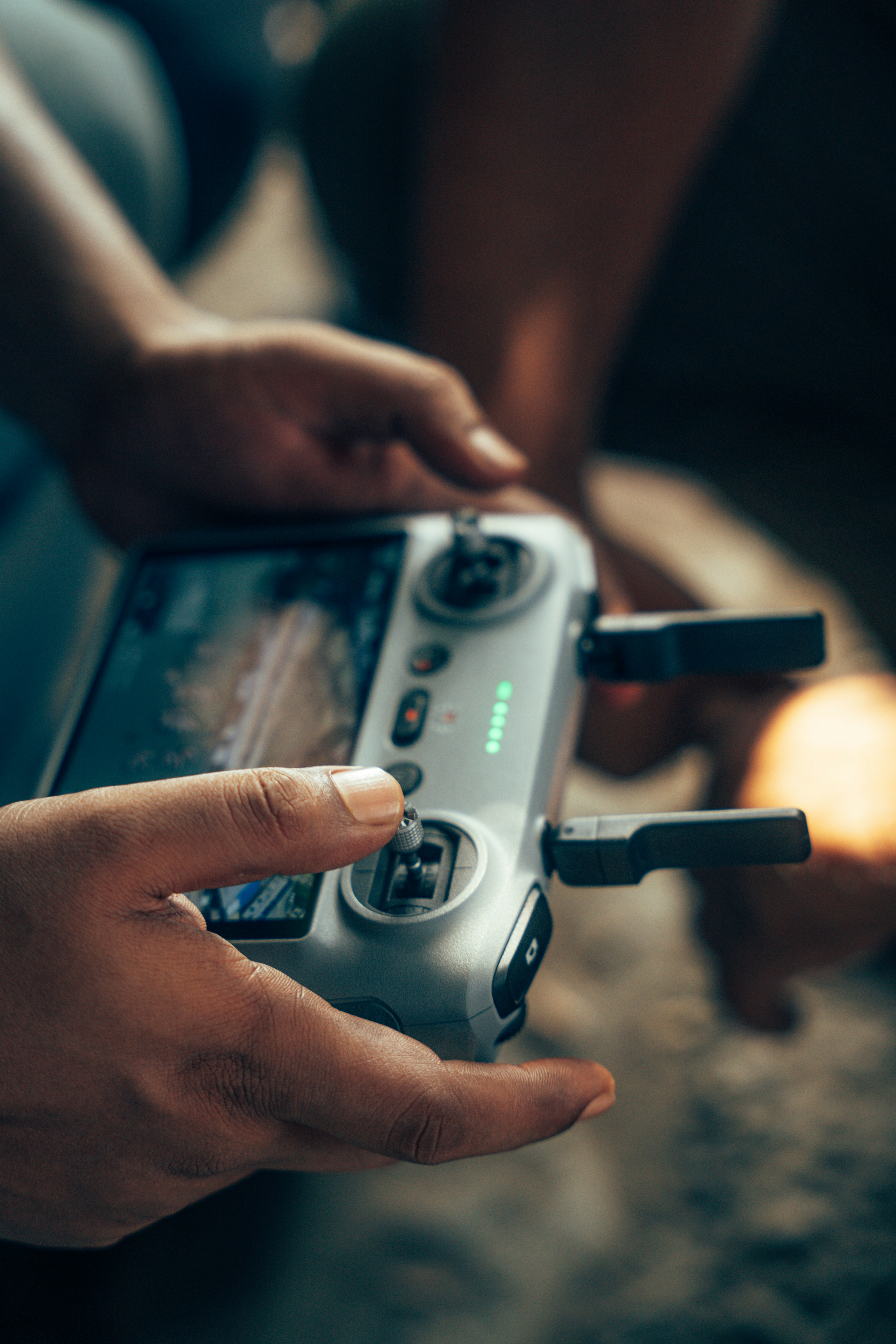 A person holding a grey drone remote controller with a built-in screen