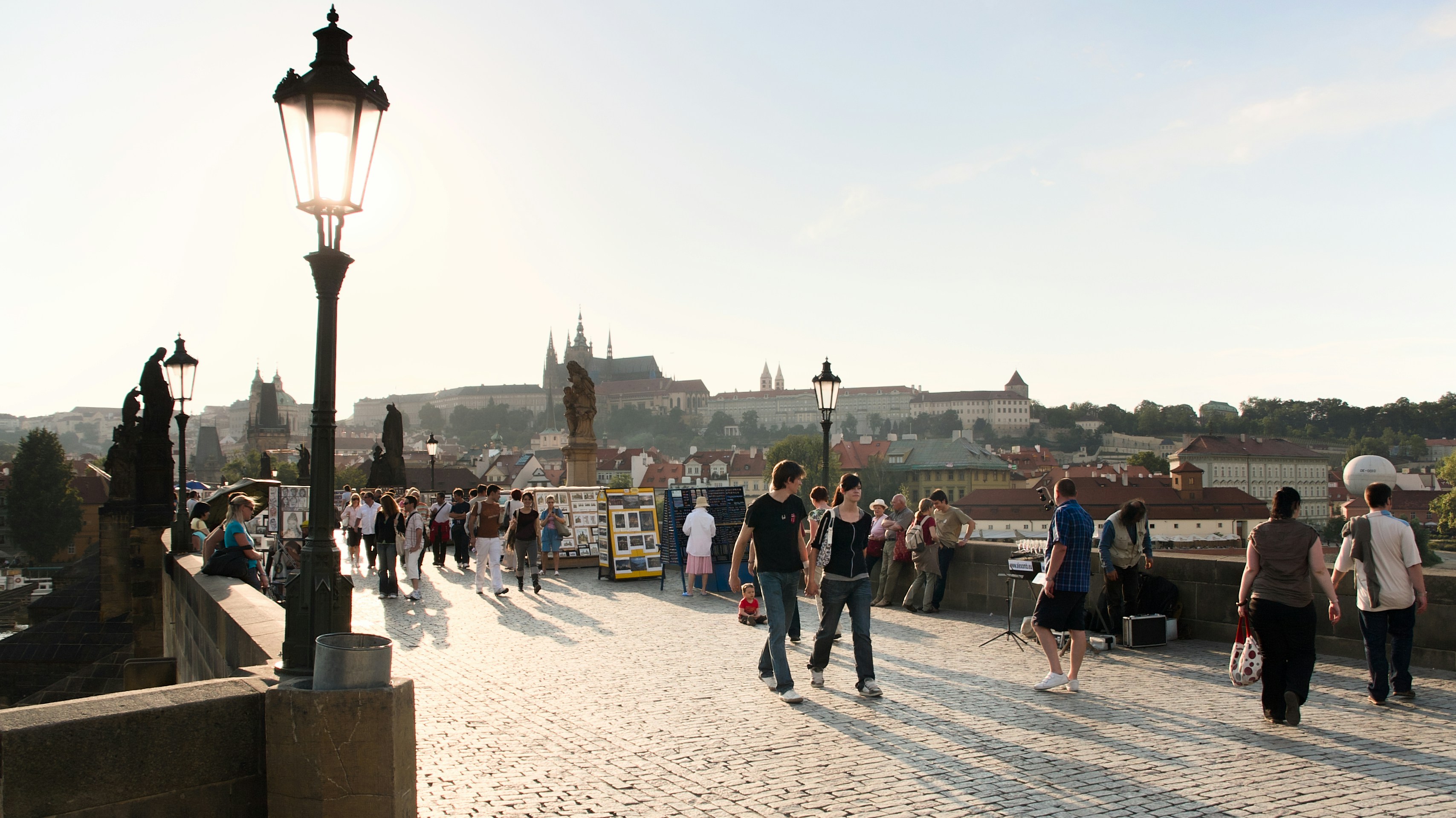 People walking on the Charles Bridge in Prague with the castle in the distance