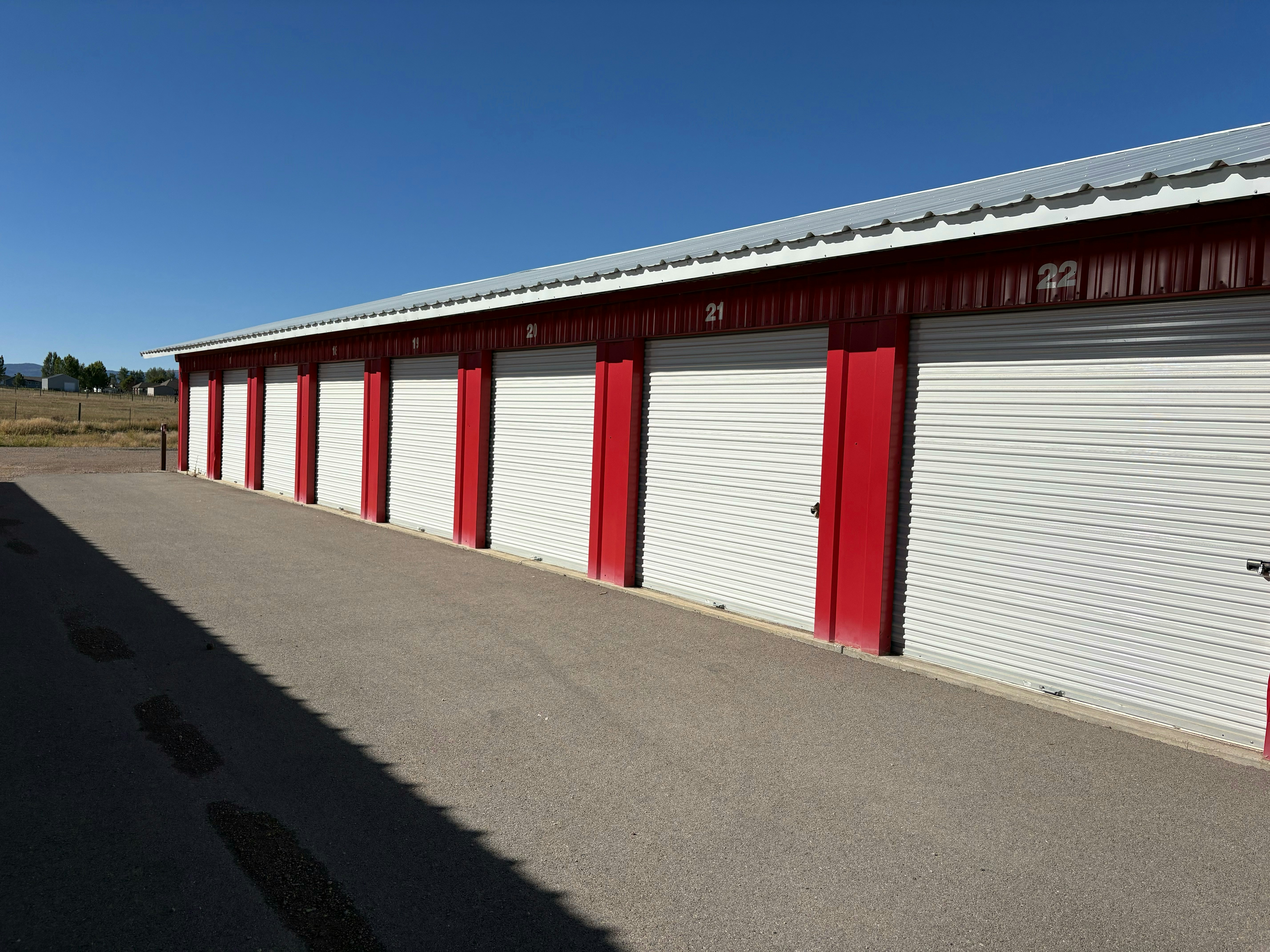 Una fila de trasteros con puertas enrollables blancas y molduras metálicas rojas