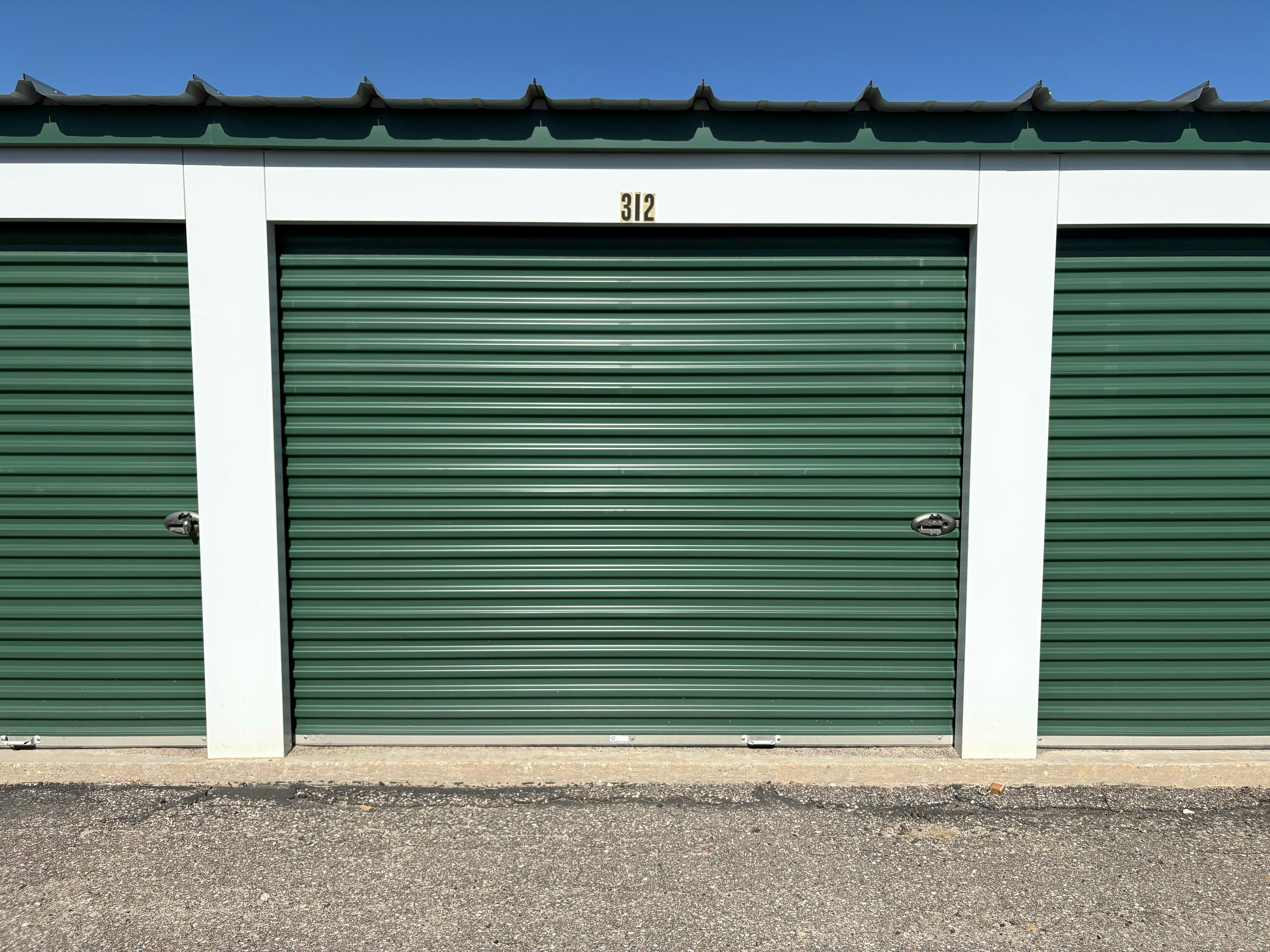Una puerta metálica verde enrollable de trastero marcada con el número 312