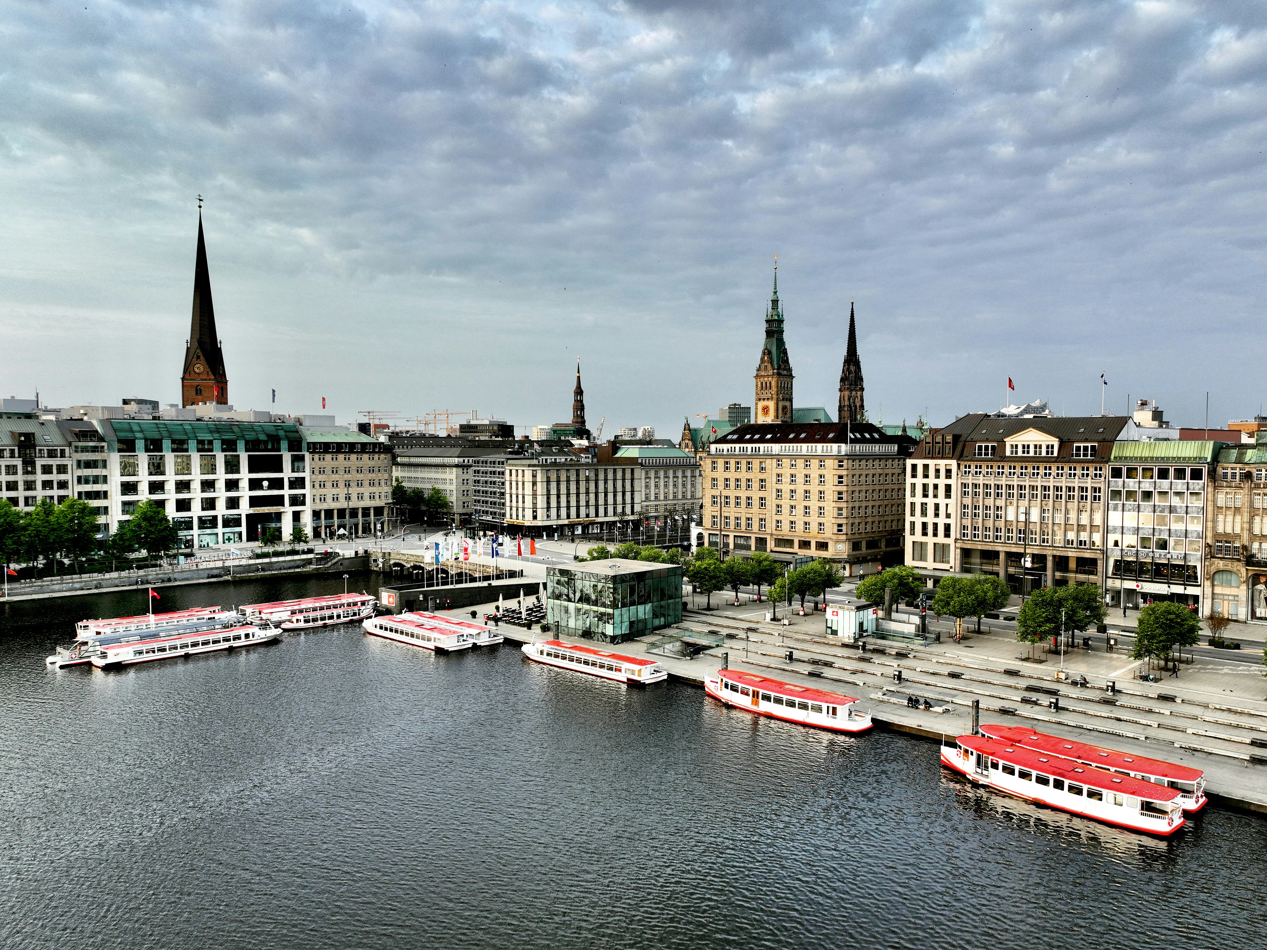 Passenger boats docked along the Binnenalster lake in Hamburg with historic spires