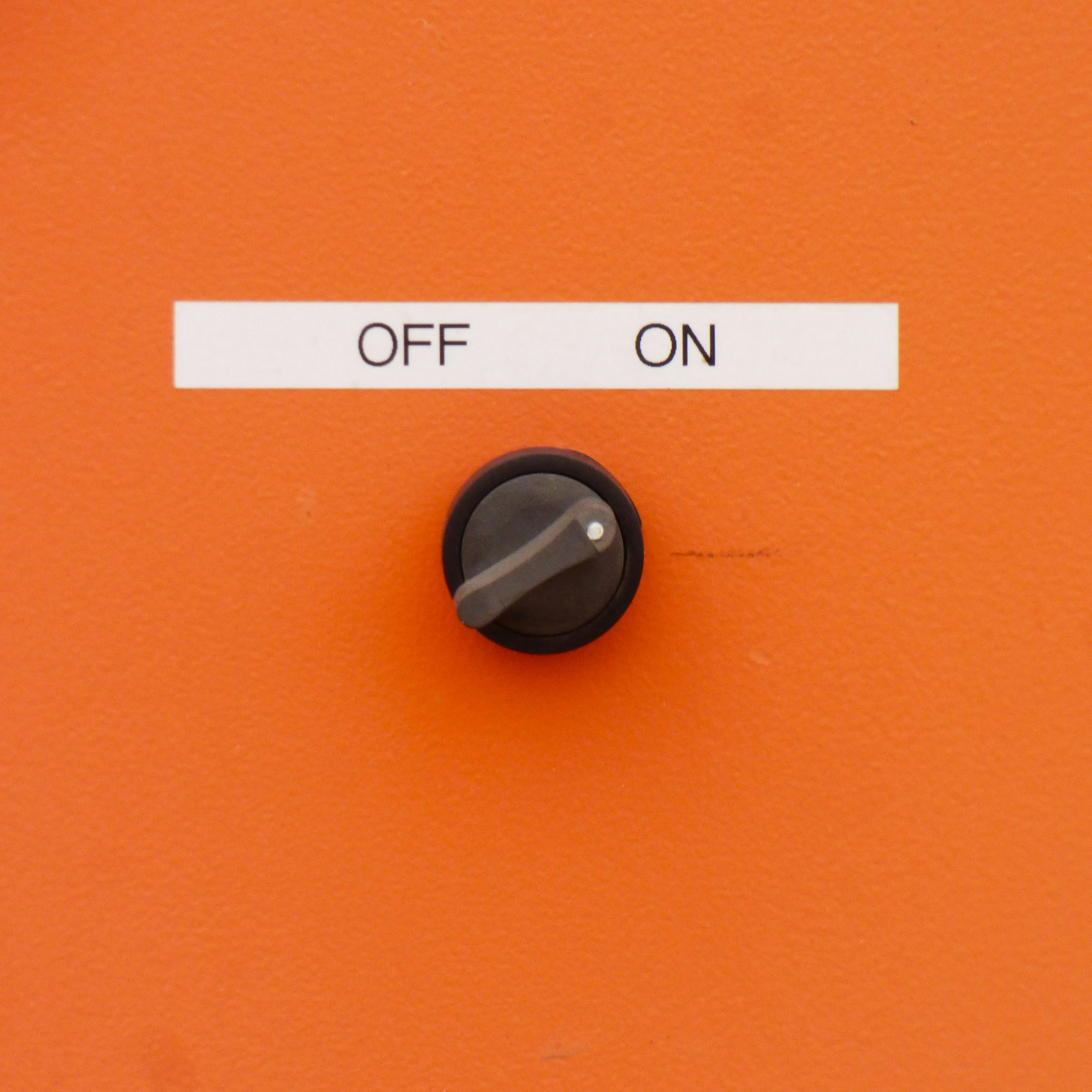 A black rotary switch on an orange surface with labels reading OFF and ON