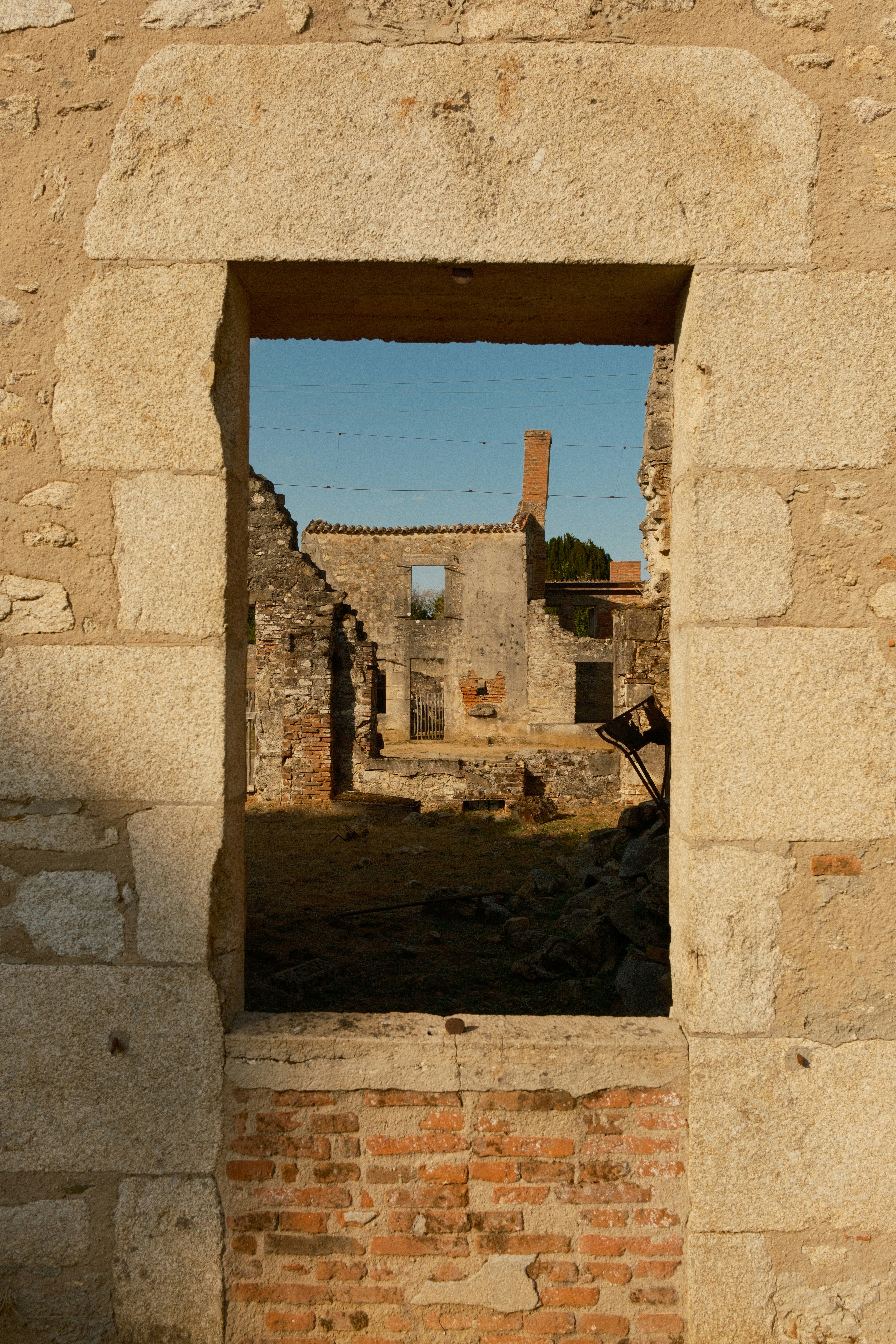 A view through a stone window frame of crumbling brick and stone ruins