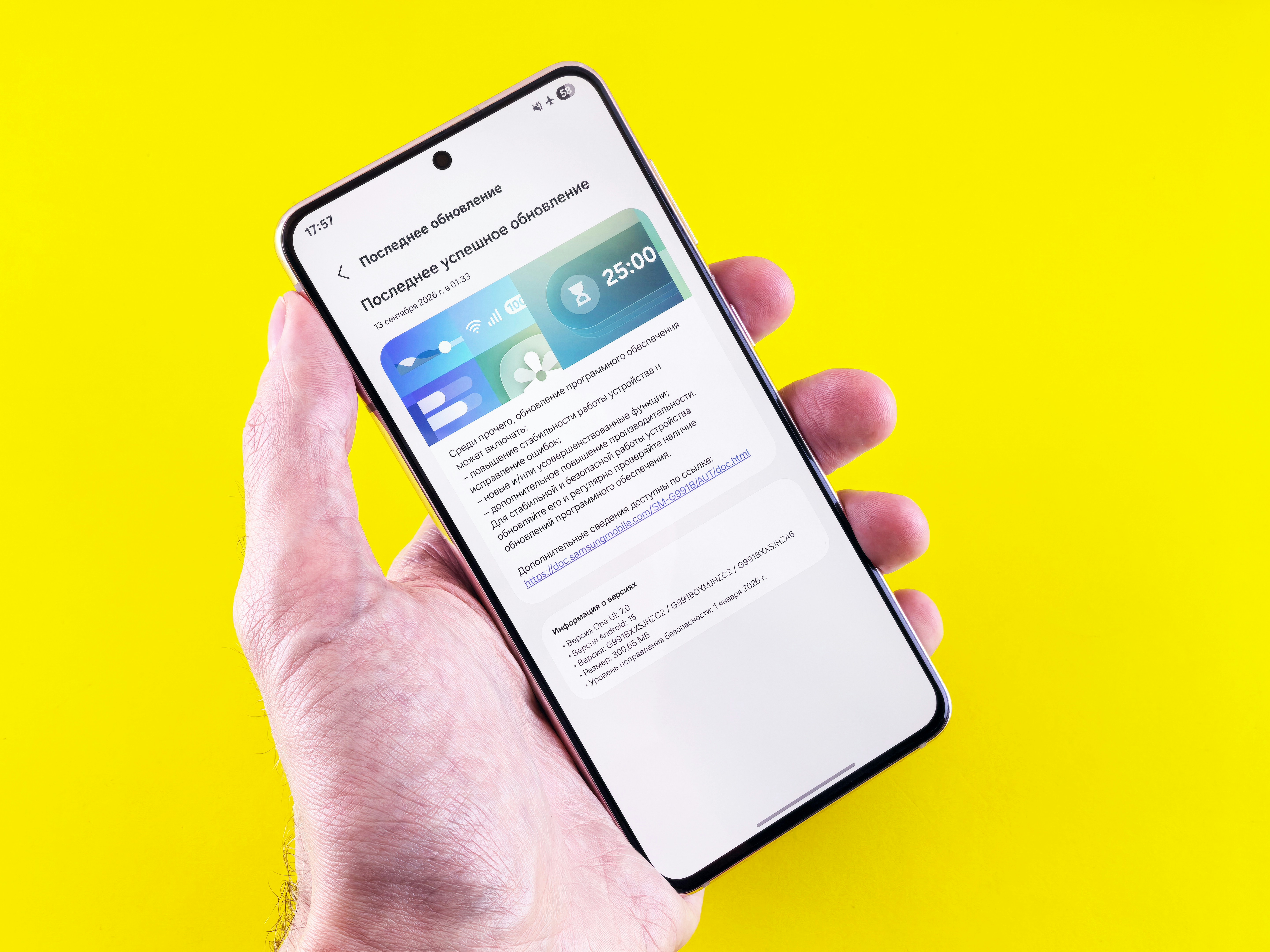 A hand holding a smartphone displaying a software update screen against a yellow background