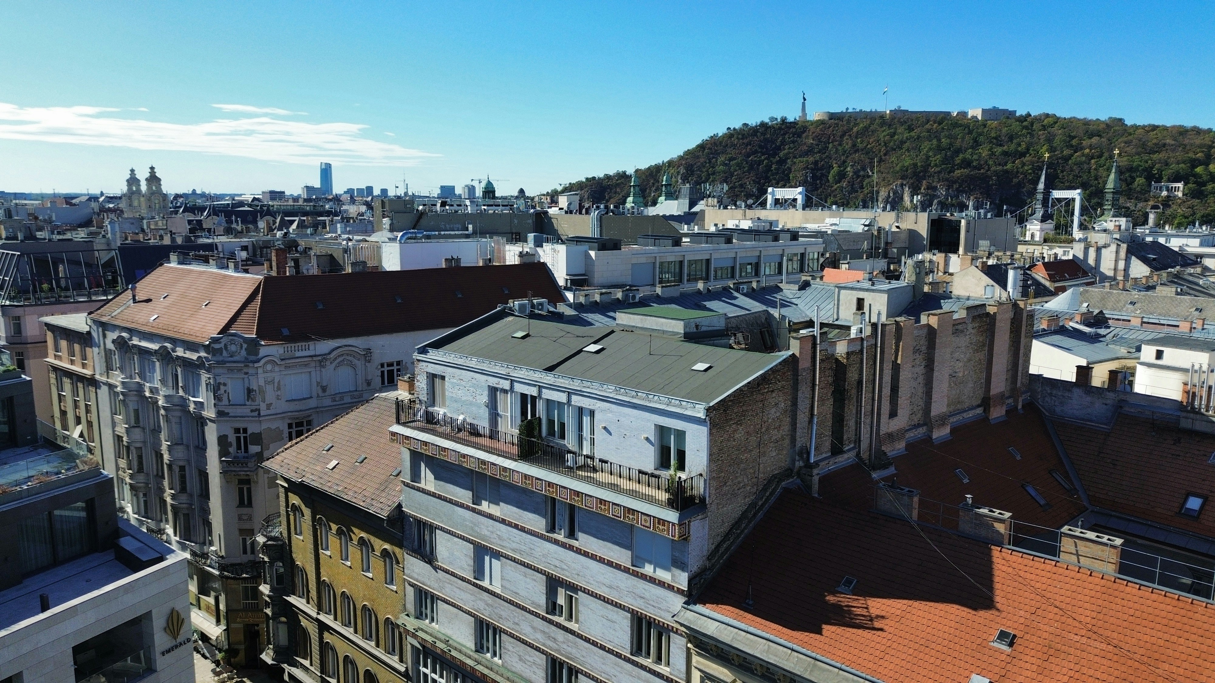 Aerial view of rooftops and buildings in Budapest with Gellert Hill in the distance