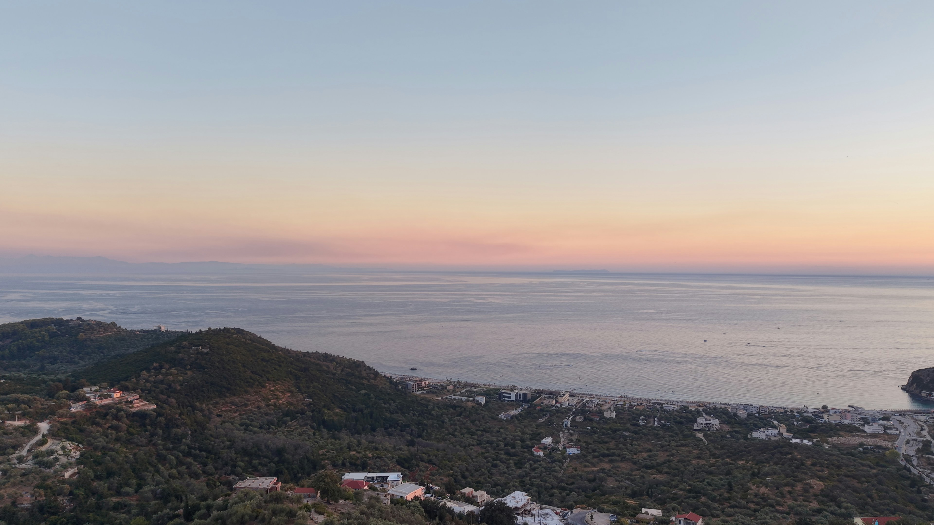 Aerial view of a coastal town with hills and the sea at golden hour