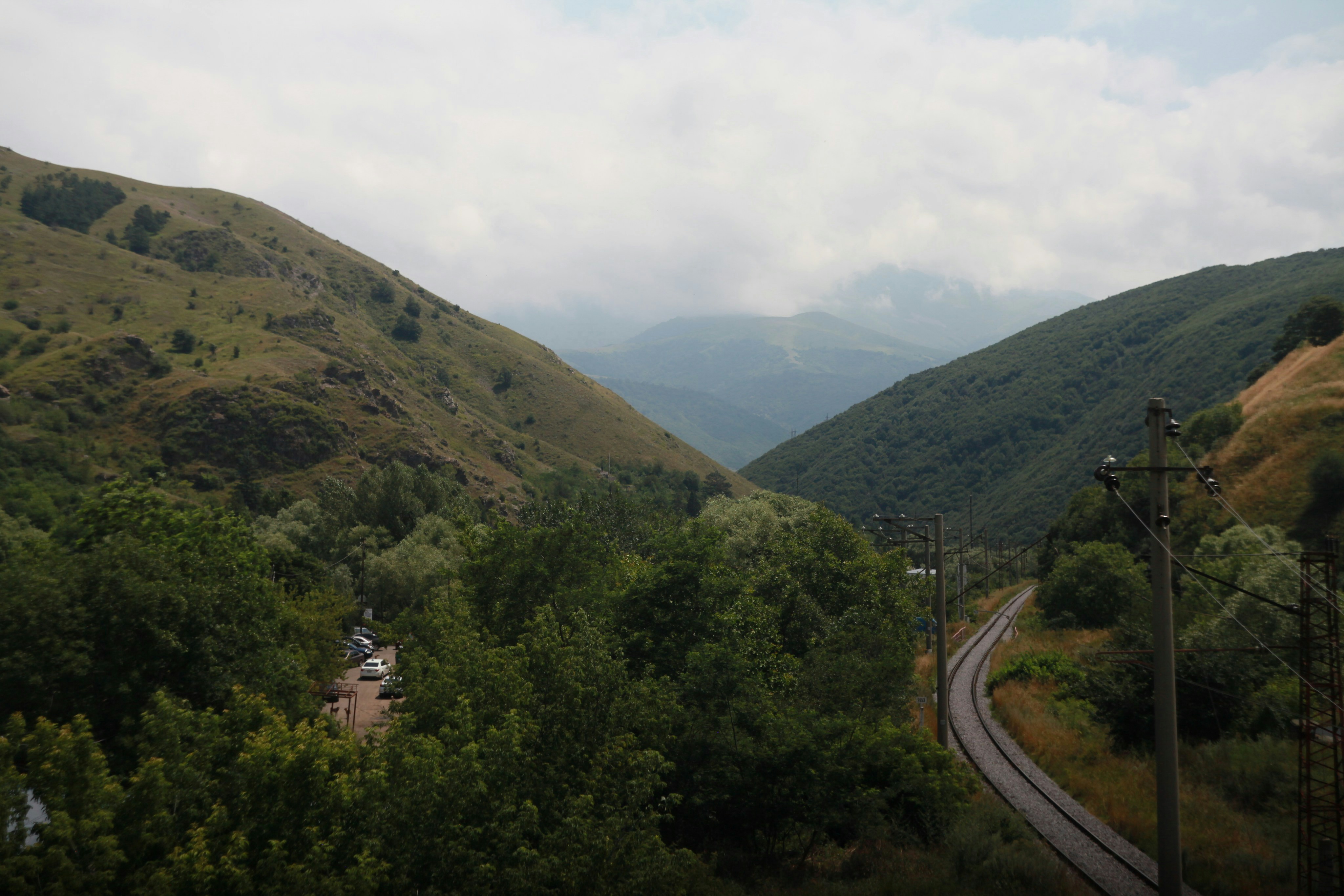 A railway track curving through a green valley between two mountain slopes