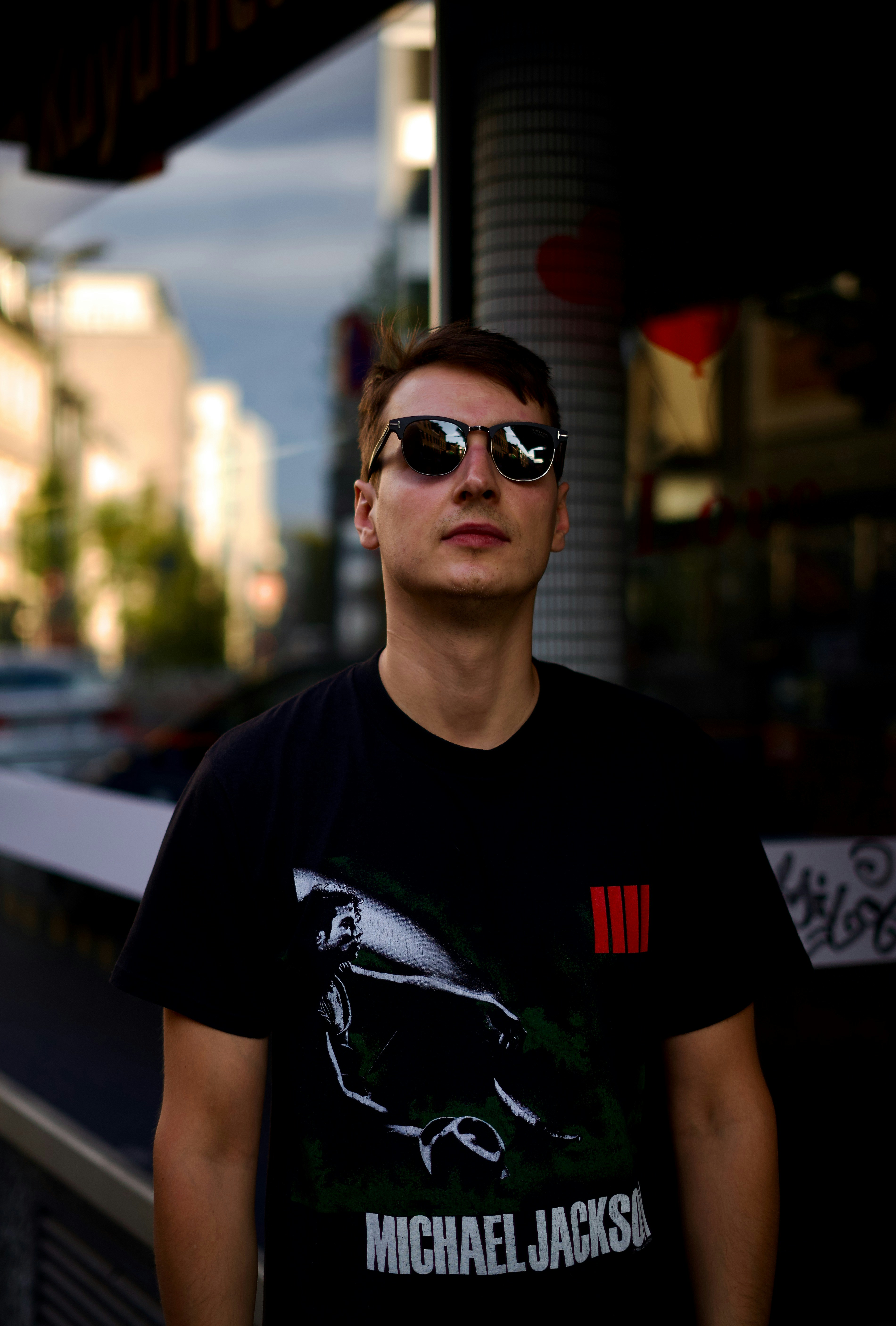 A man wearing sunglasses and a black graphic t-shirt on a city street