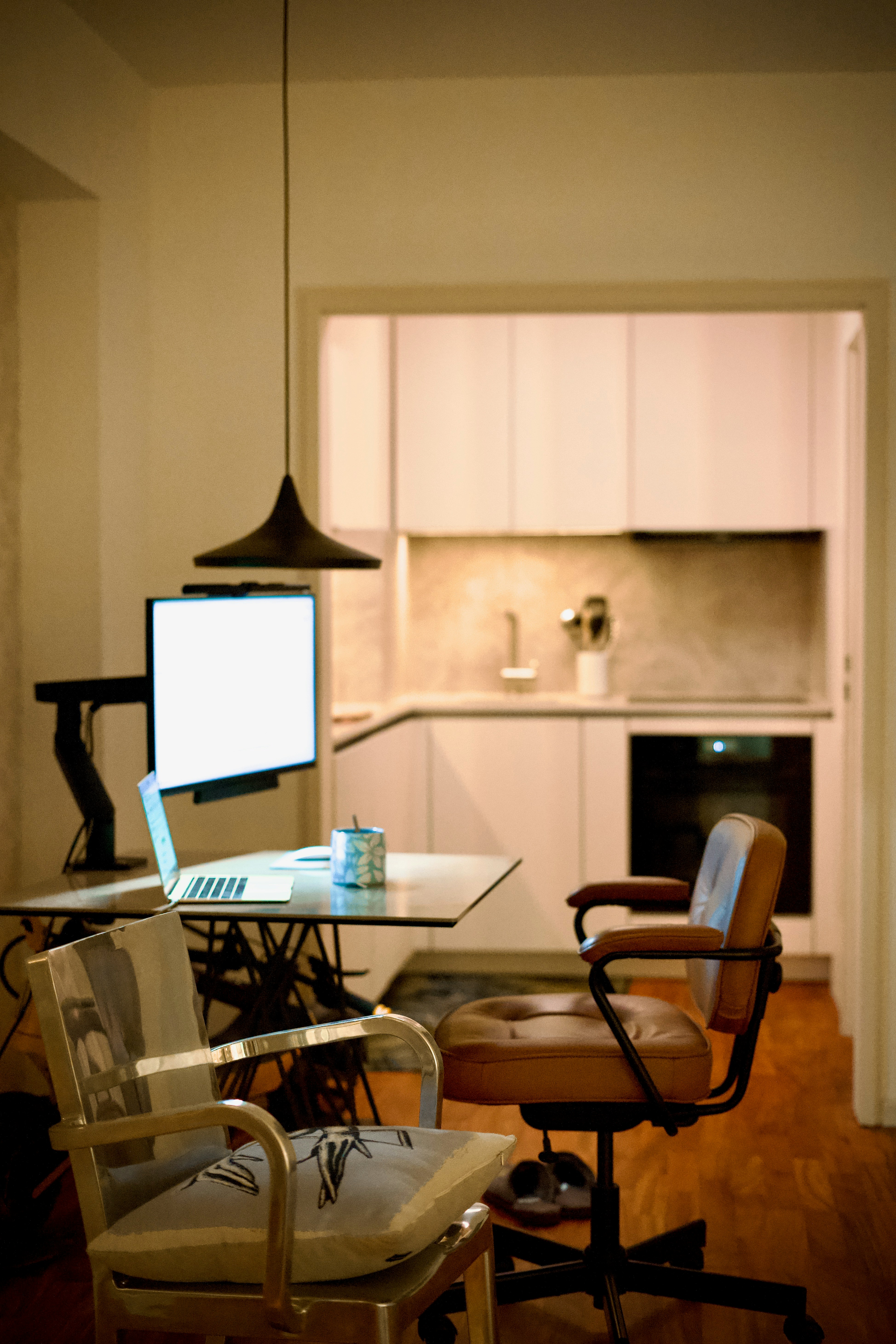 A home office desk with a laptop and monitor in a kitchen