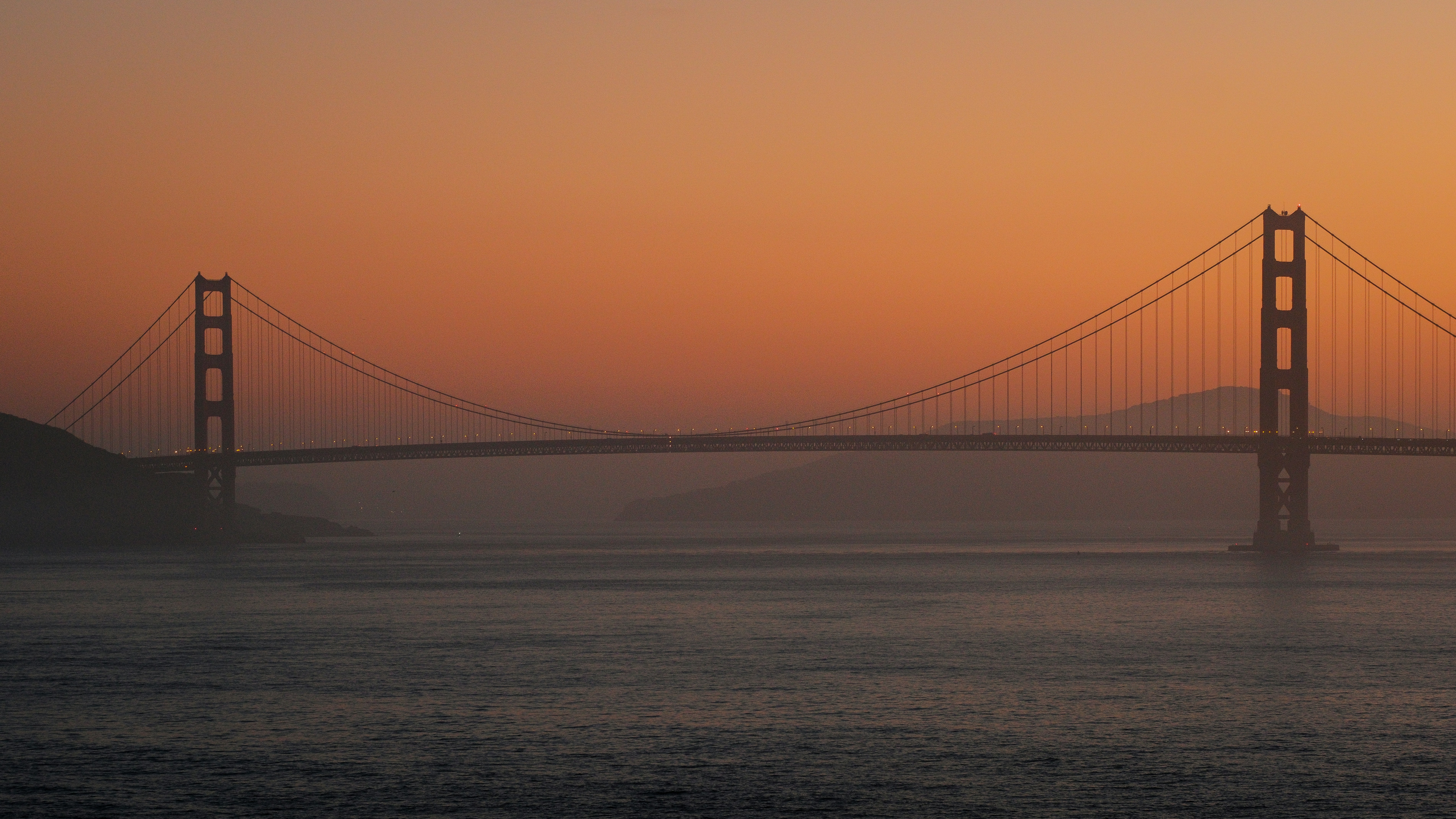 The Golden Gate Bridge in San Francisco under a warm orange sky