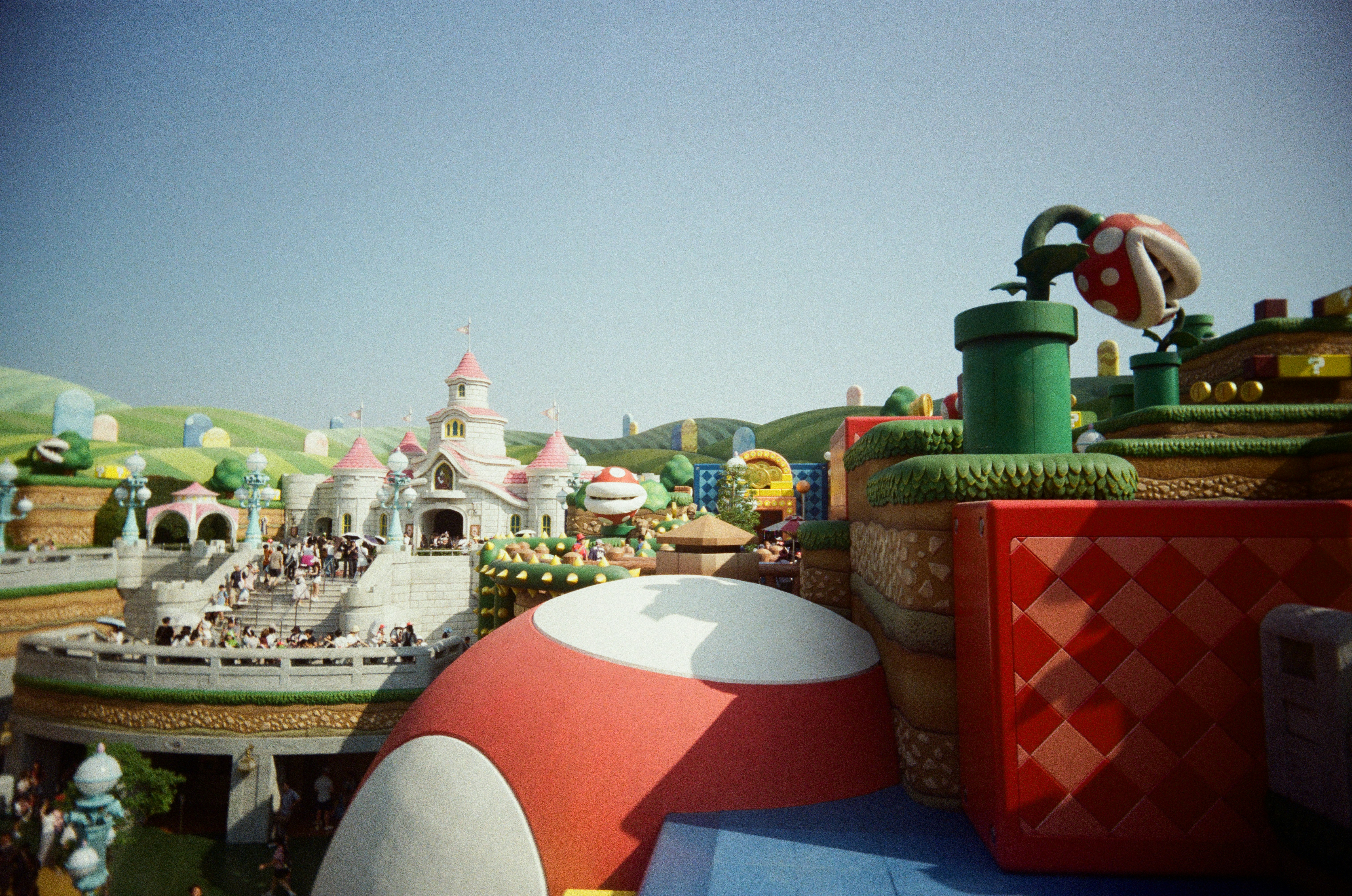 A colorful theme park with a castle and piranha plants in a landscape