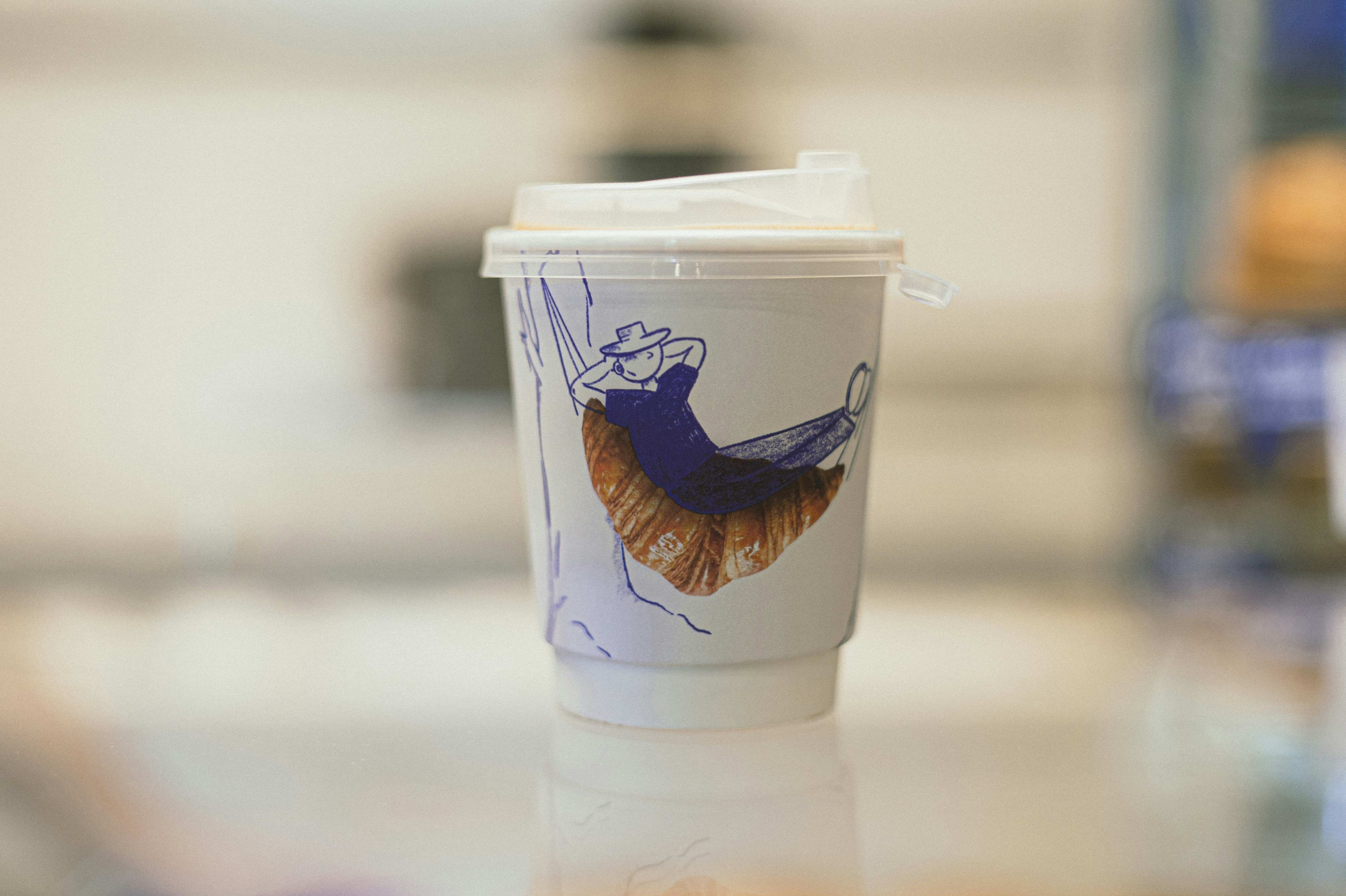 Paper coffee cup with a croissant drawing