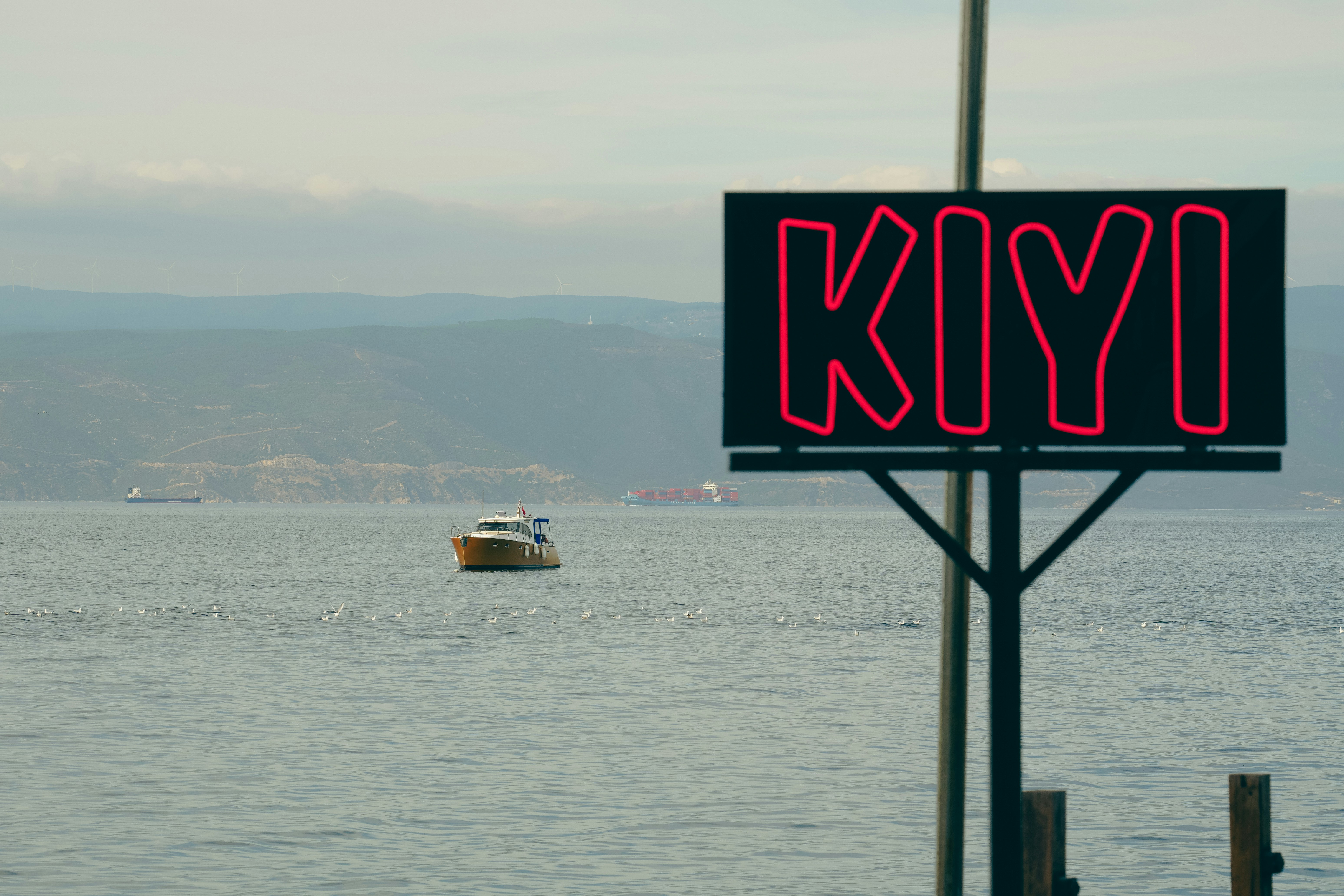 A small boat on the sea with a neon sign reading KIYI in the foreground