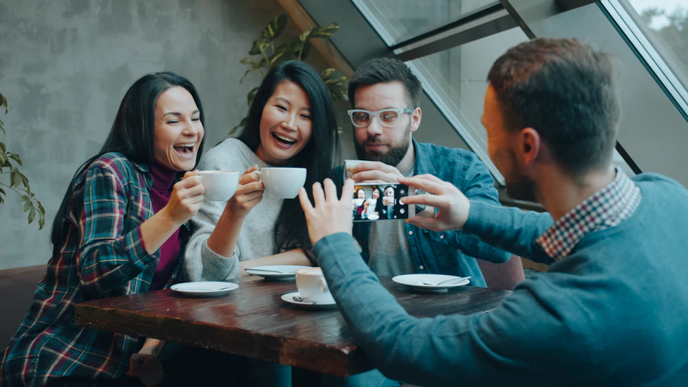 Friends laughing while taking a selfie at a café table