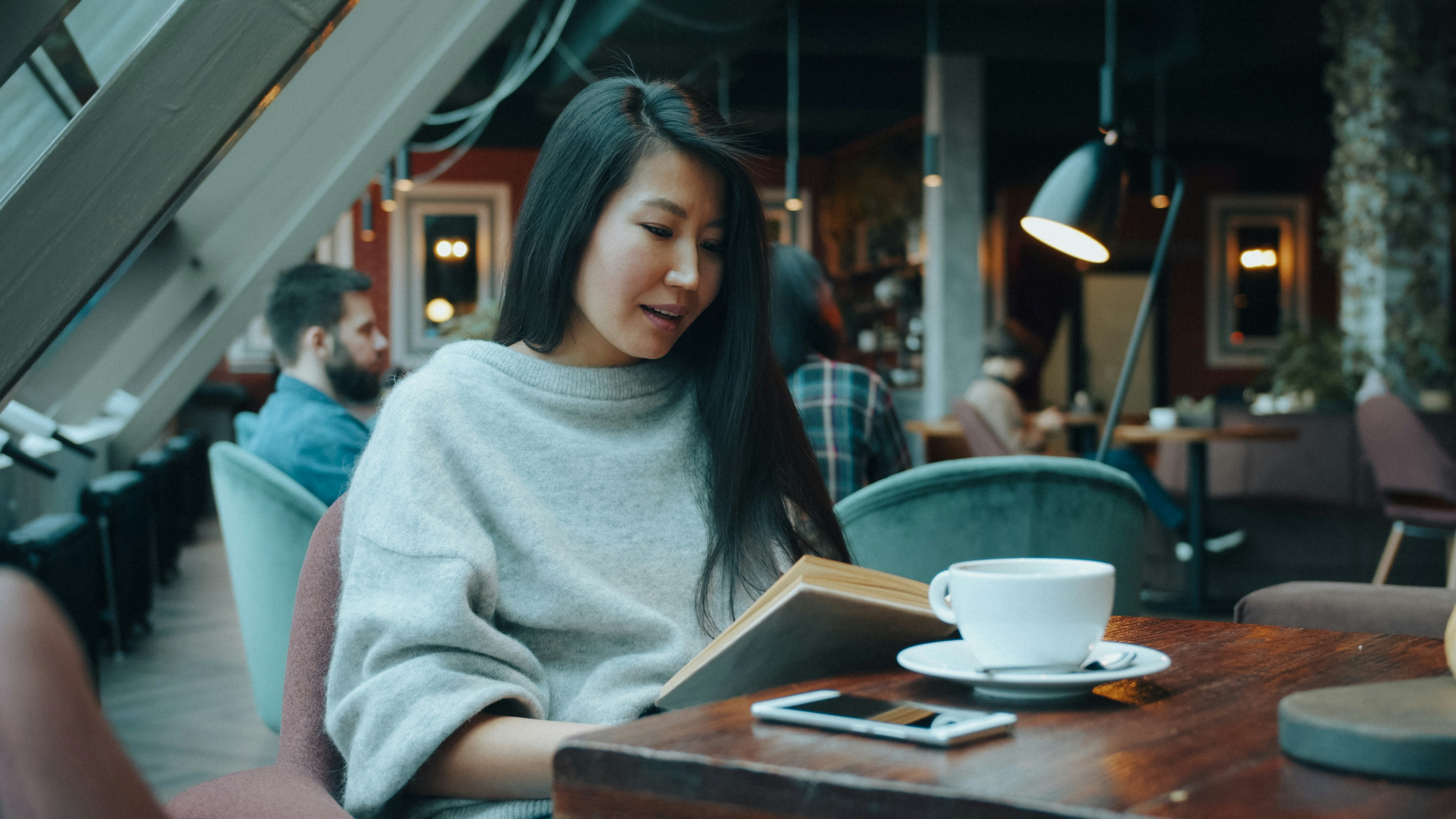 Woman in a grey sweater reading a book