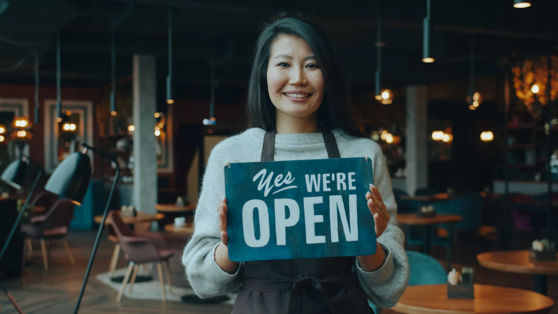Chủ doanh nghiệp đứng trước cửa tiệm của mình