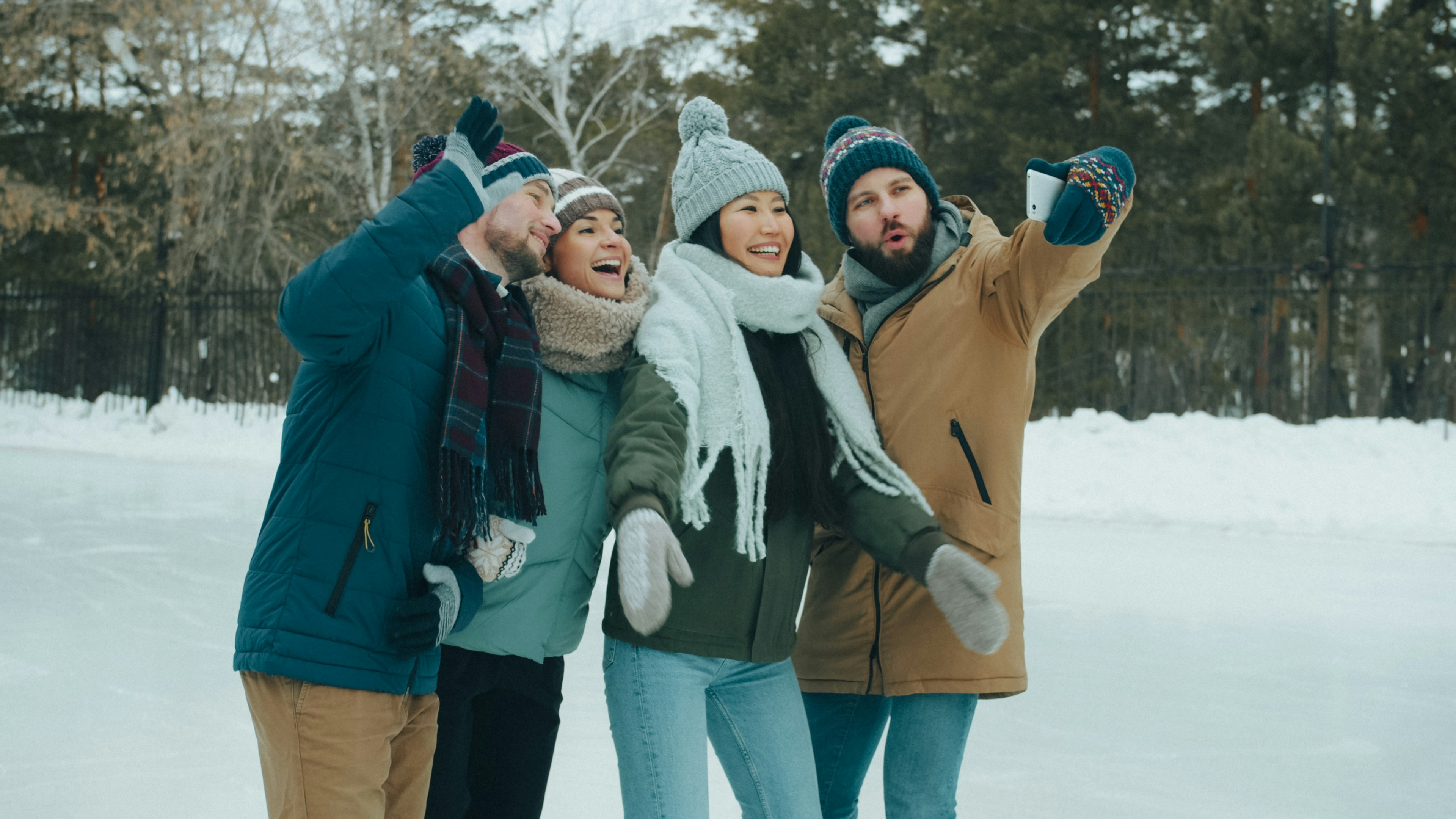 Four people in winter clothing taking a selfie on an outdoor ice rink