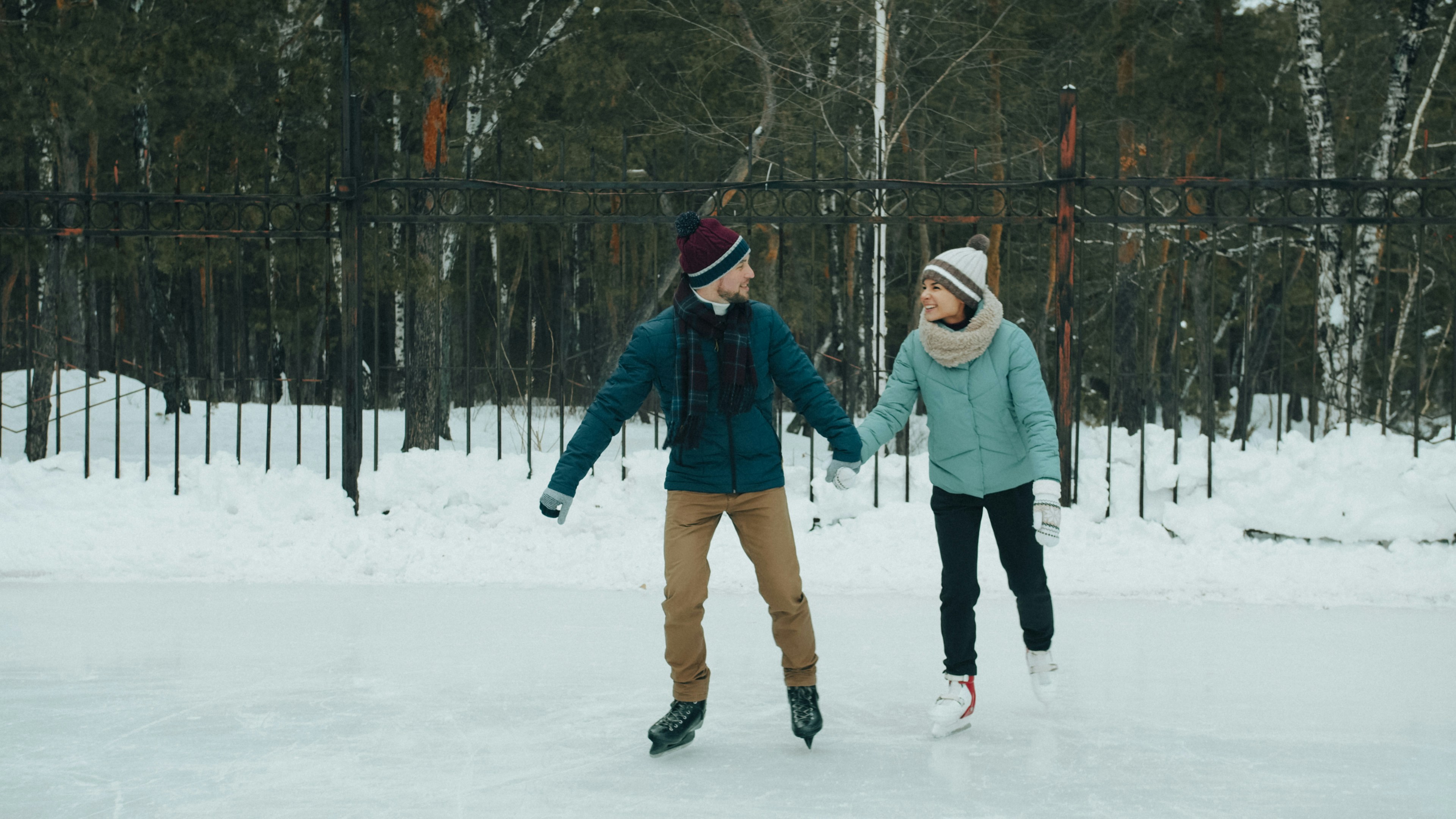 A man and a woman ice skating together on an outdoor rink