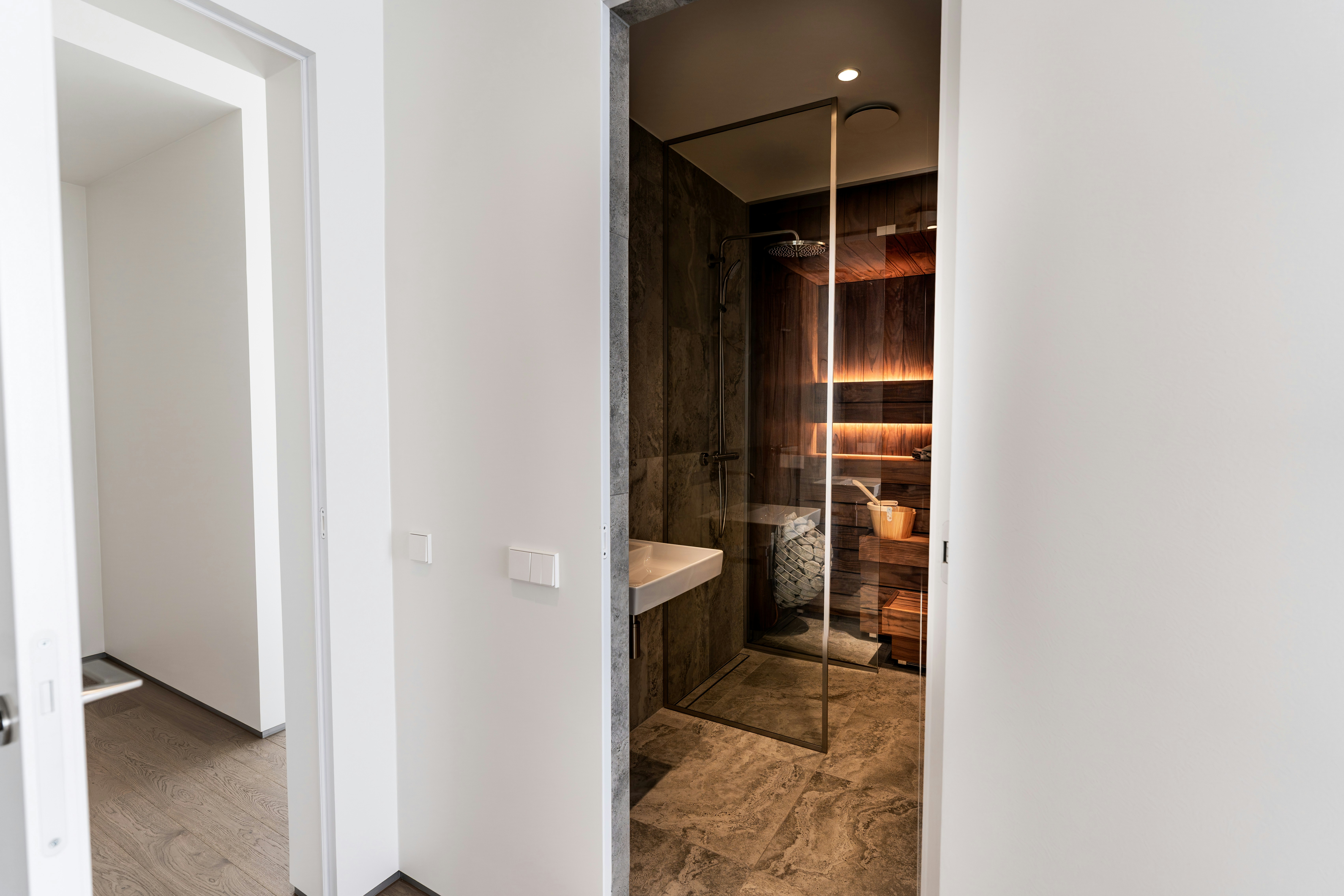 A modern bathroom with a glass shower and wooden sauna interior