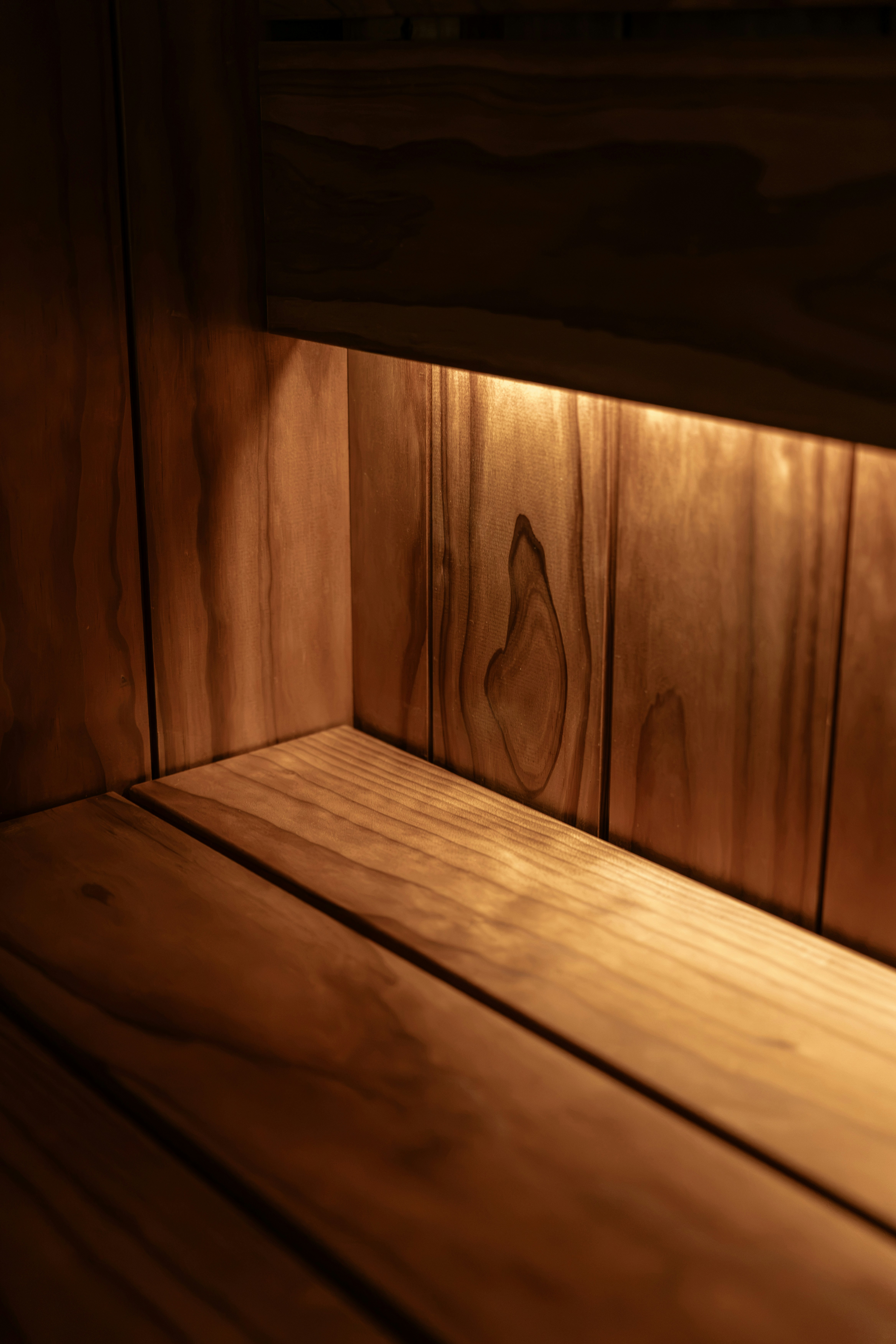 A wooden shelf illuminated by warm light from a hidden source above