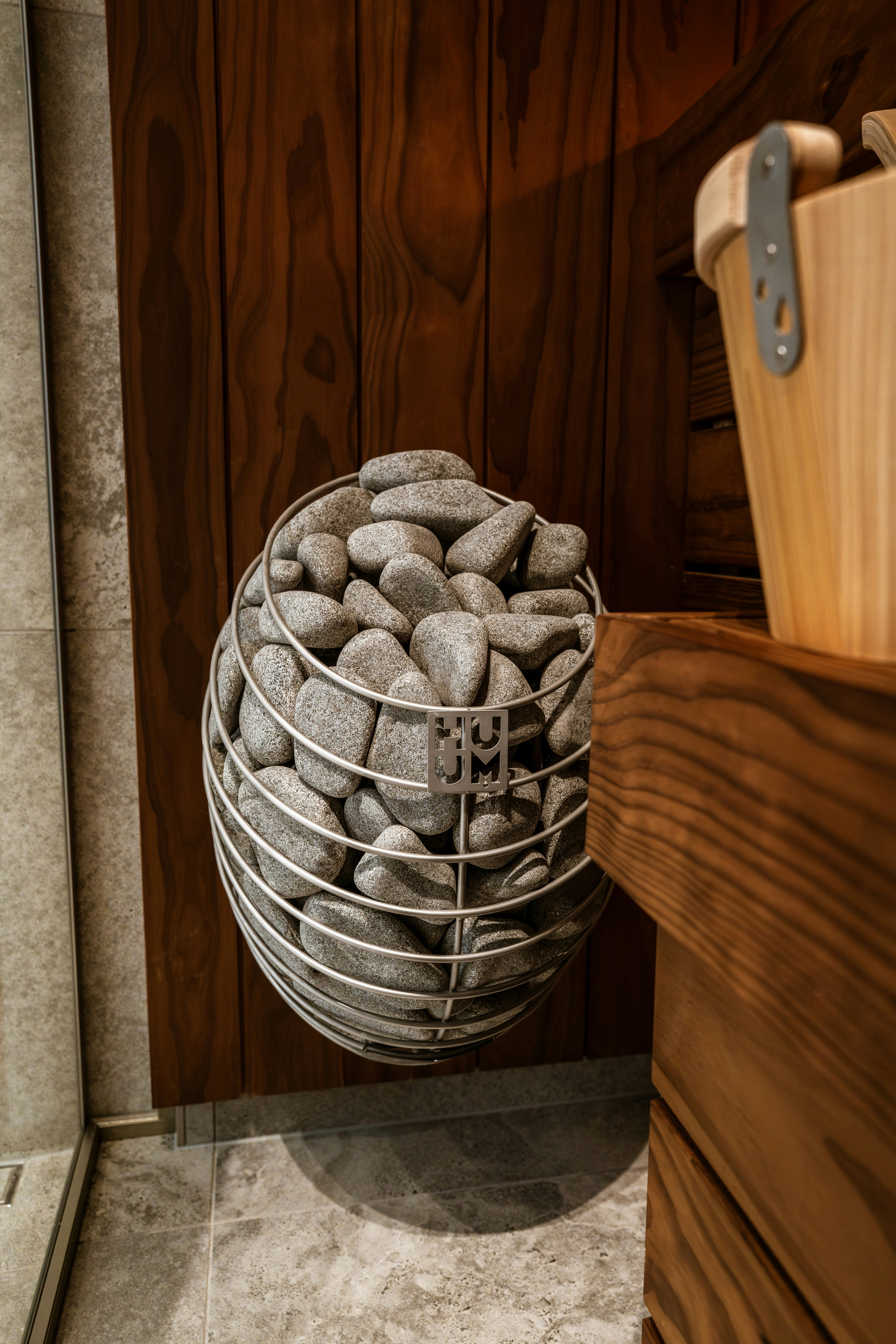 A metal cage filled with grey stones mounted on a wooden wall