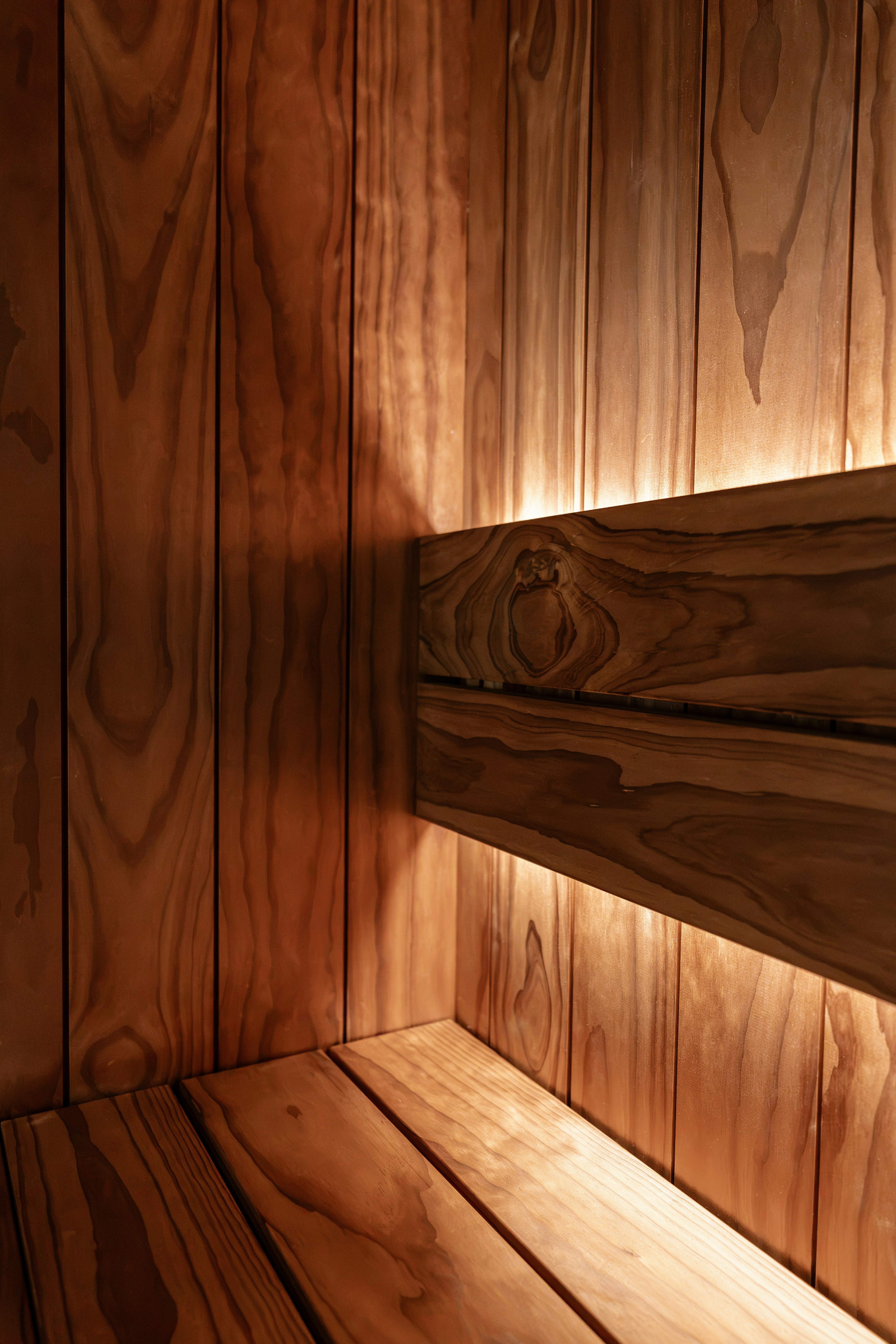 Warm light glowing behind a wooden bench in a cedar sauna interior