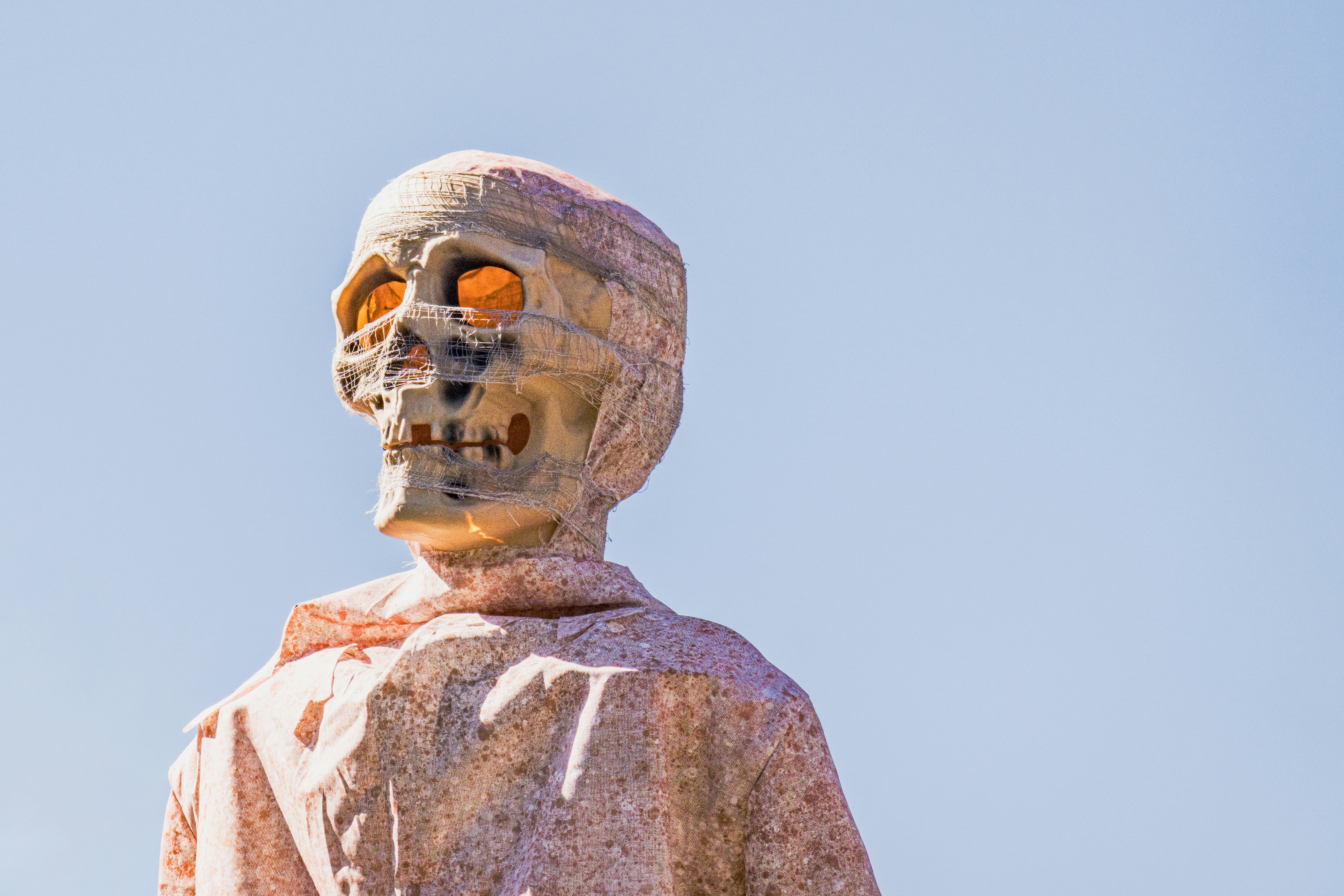 A skull wrapped in gauze against a clear blue sky