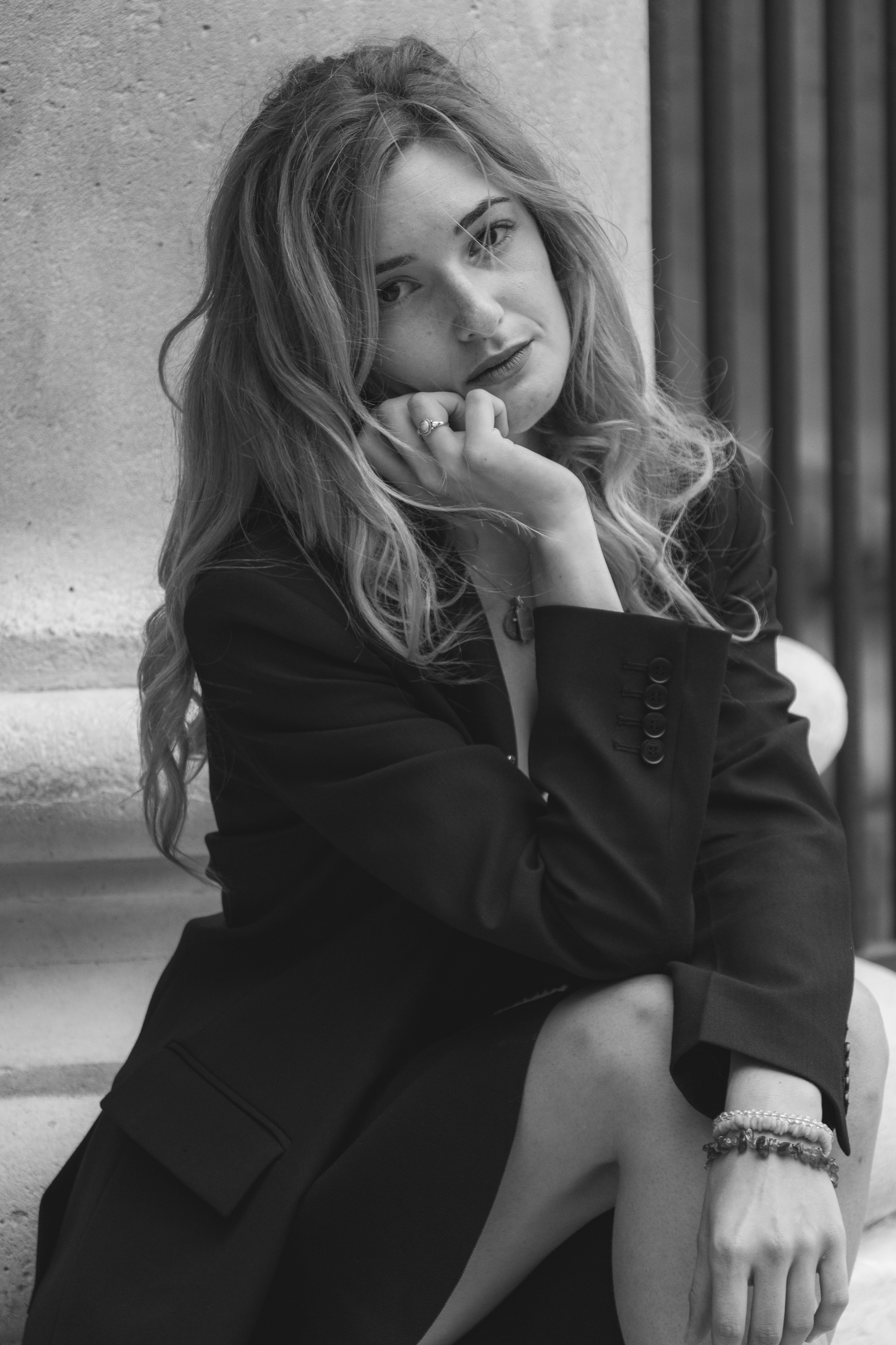 A woman in a black blazer resting her chin on her hand