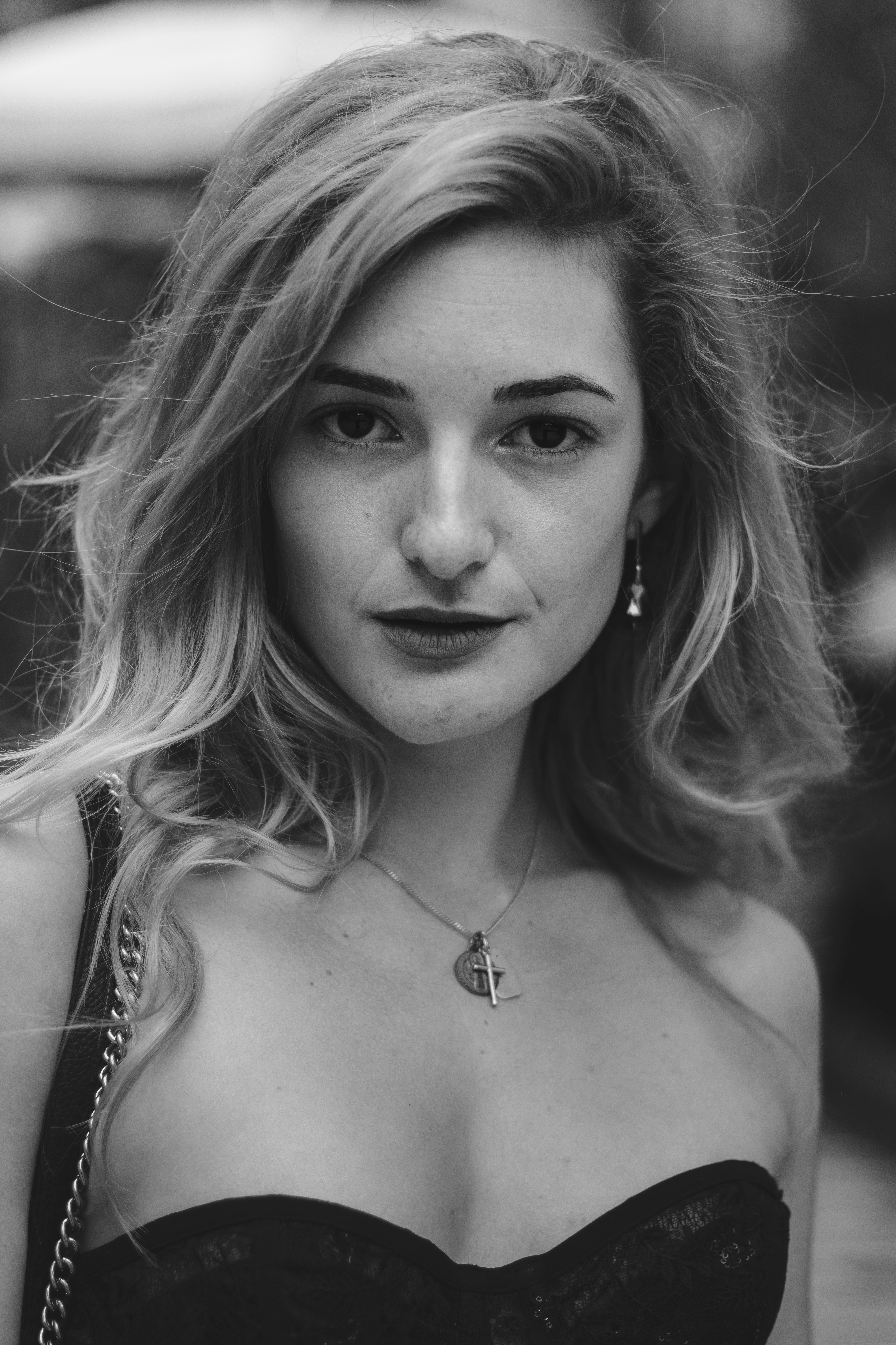 A woman with wavy blonde hair wearing a cross necklace and lace top
