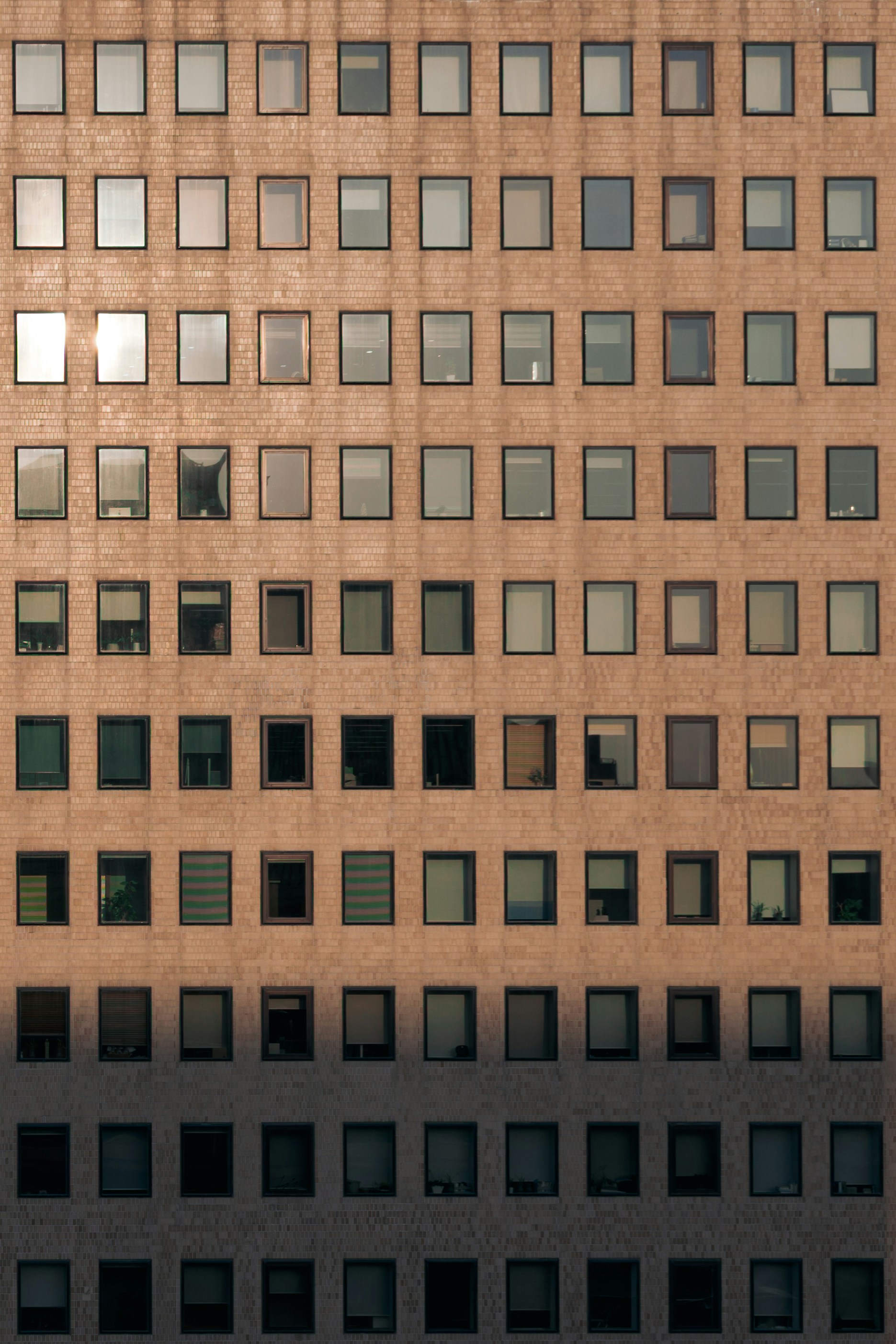 A grid of rectangular windows on a tan brick building facade