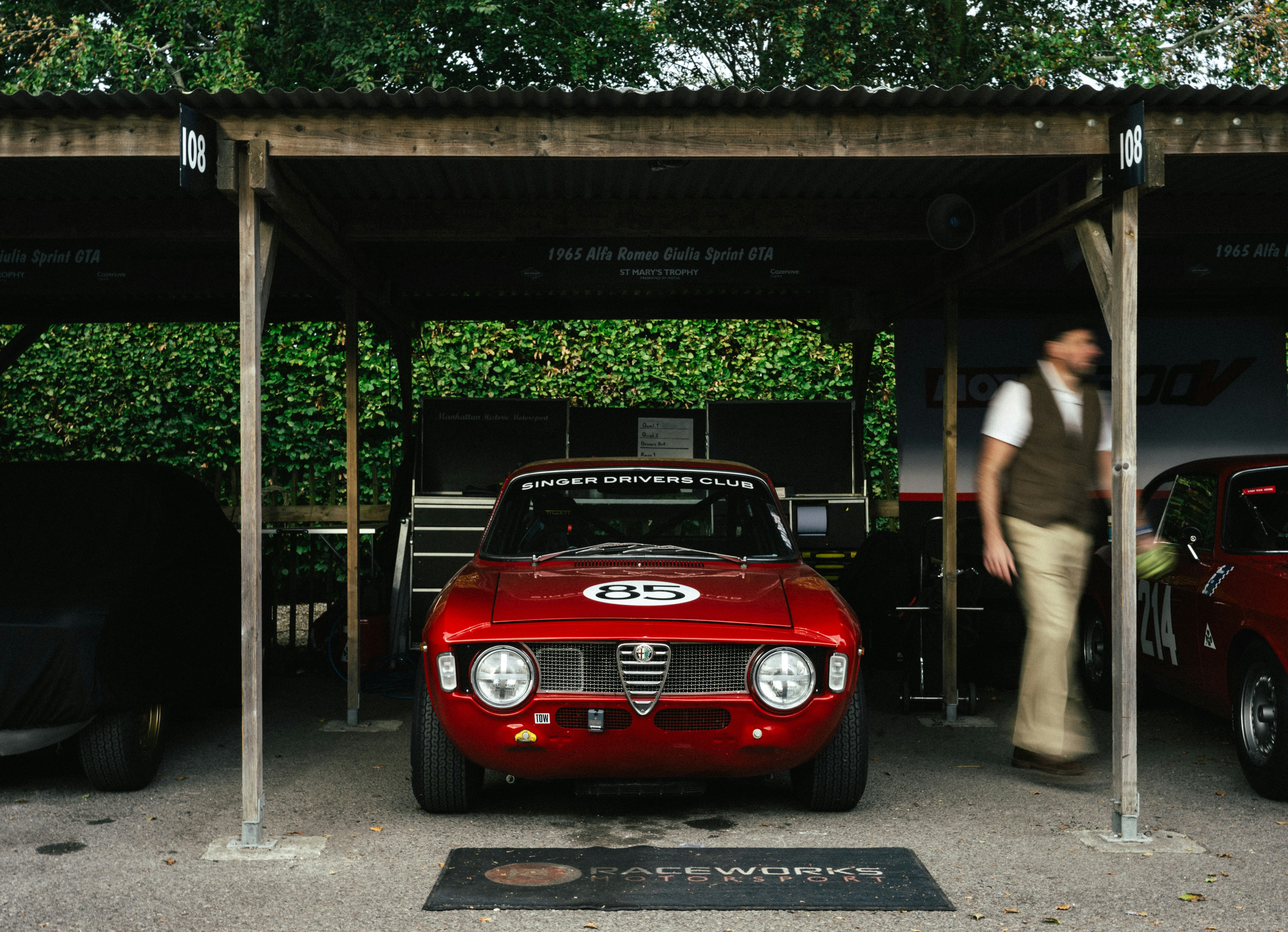 Une Alfa Romeo rouge garée dans un box en bois