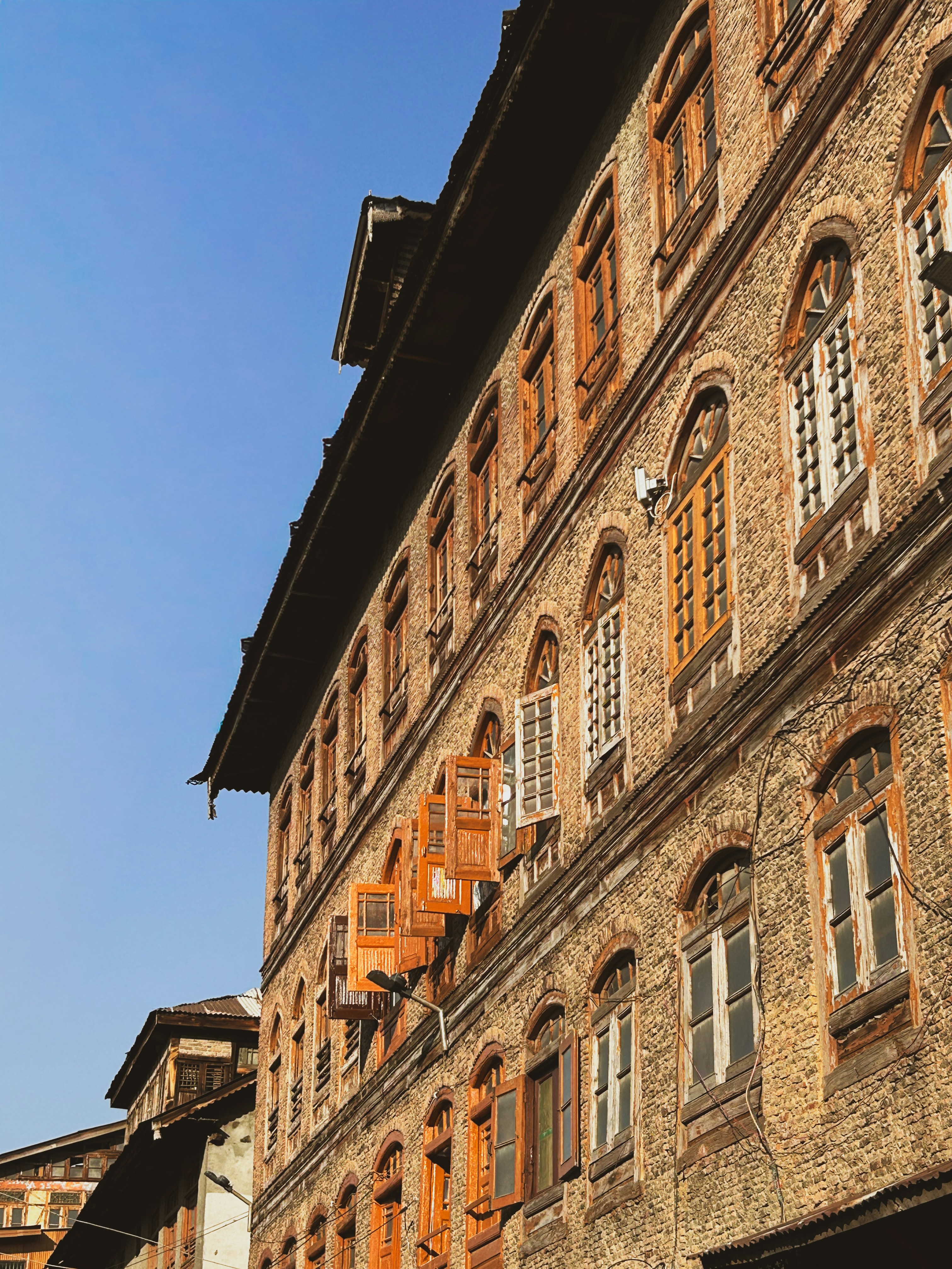 A multi-story building with weathered brick walls and many arched wooden windows