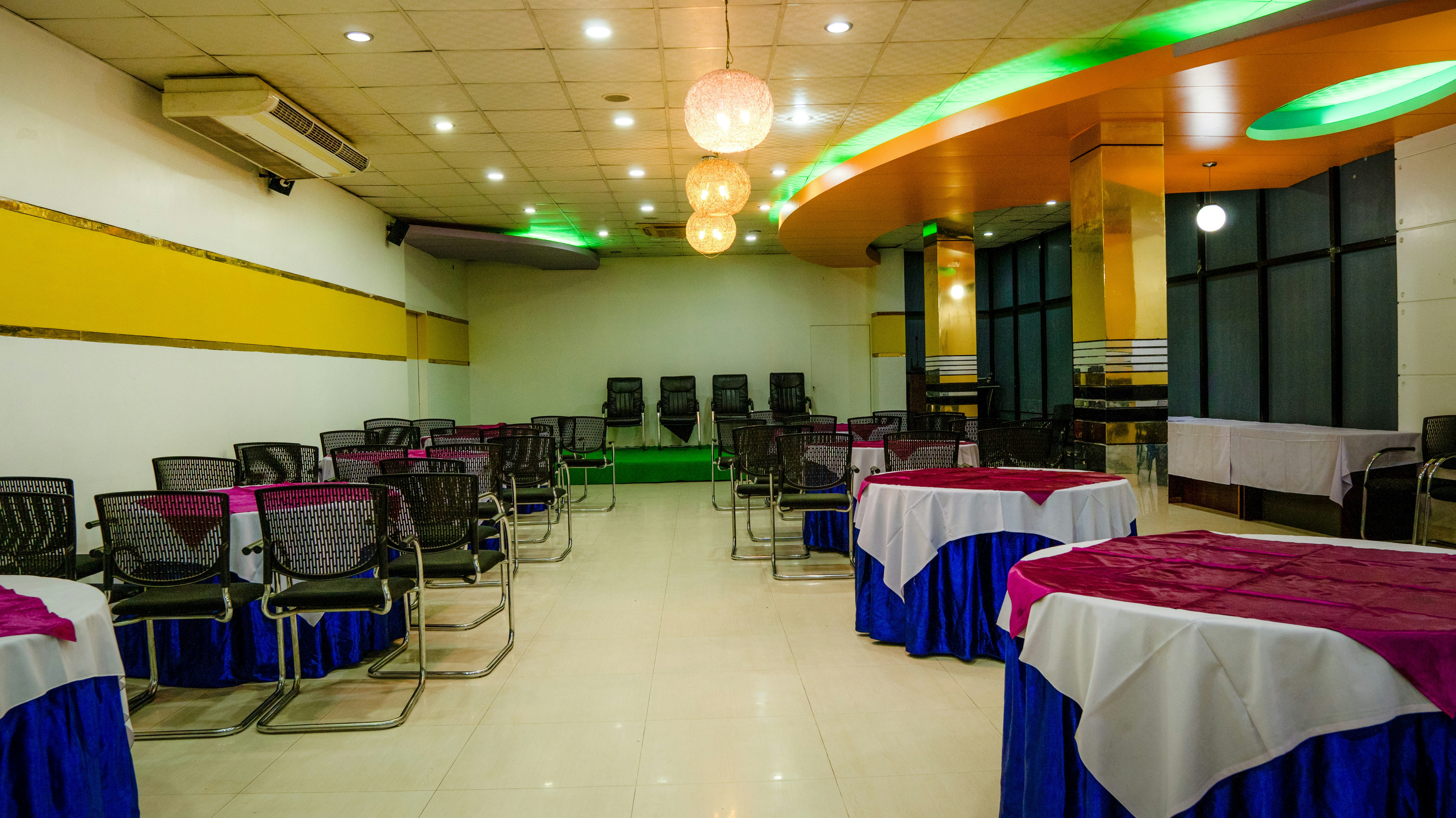 Round tables with blue and magenta cloths in a large event hall