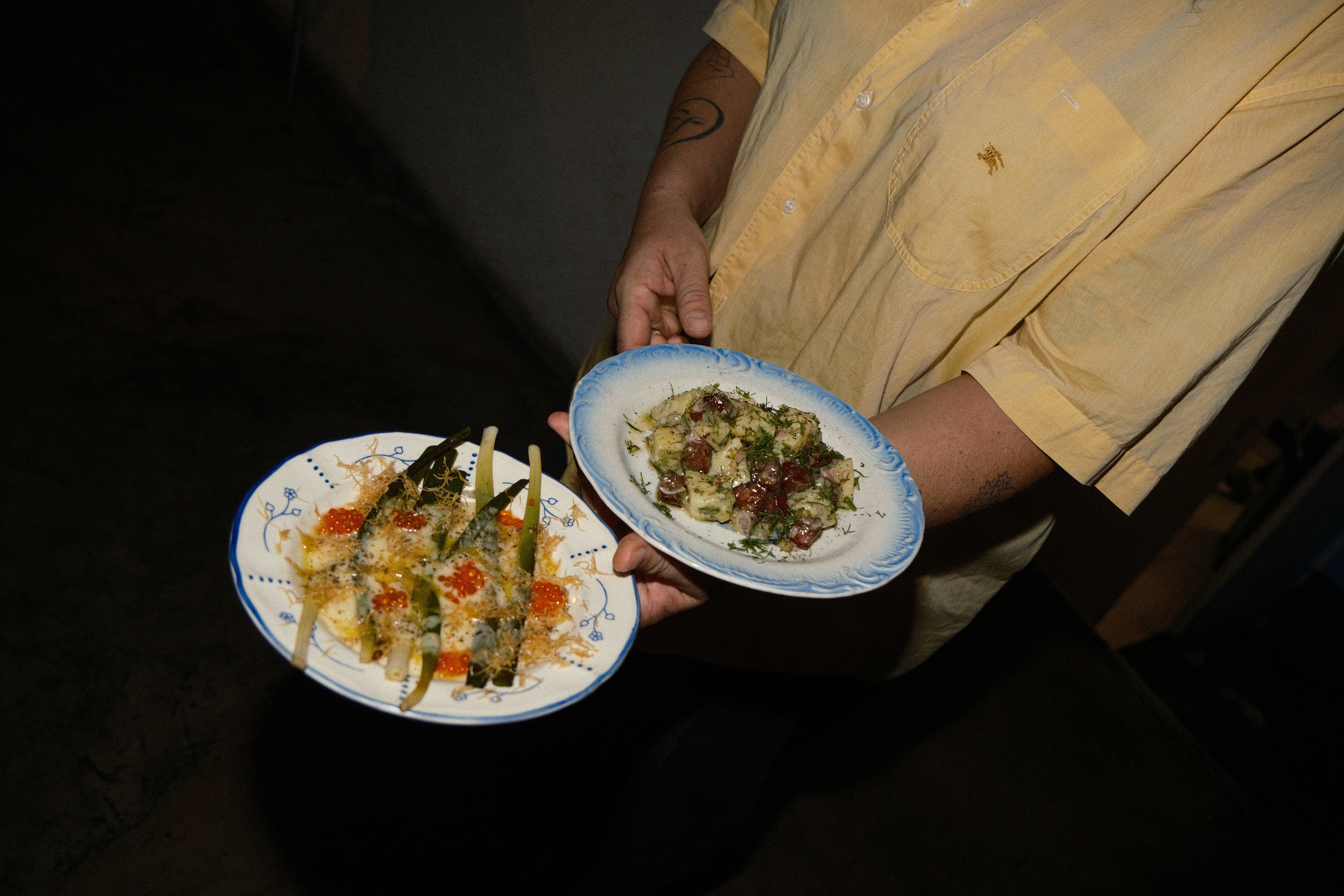 A person in a yellow shirt holding two plates of food
