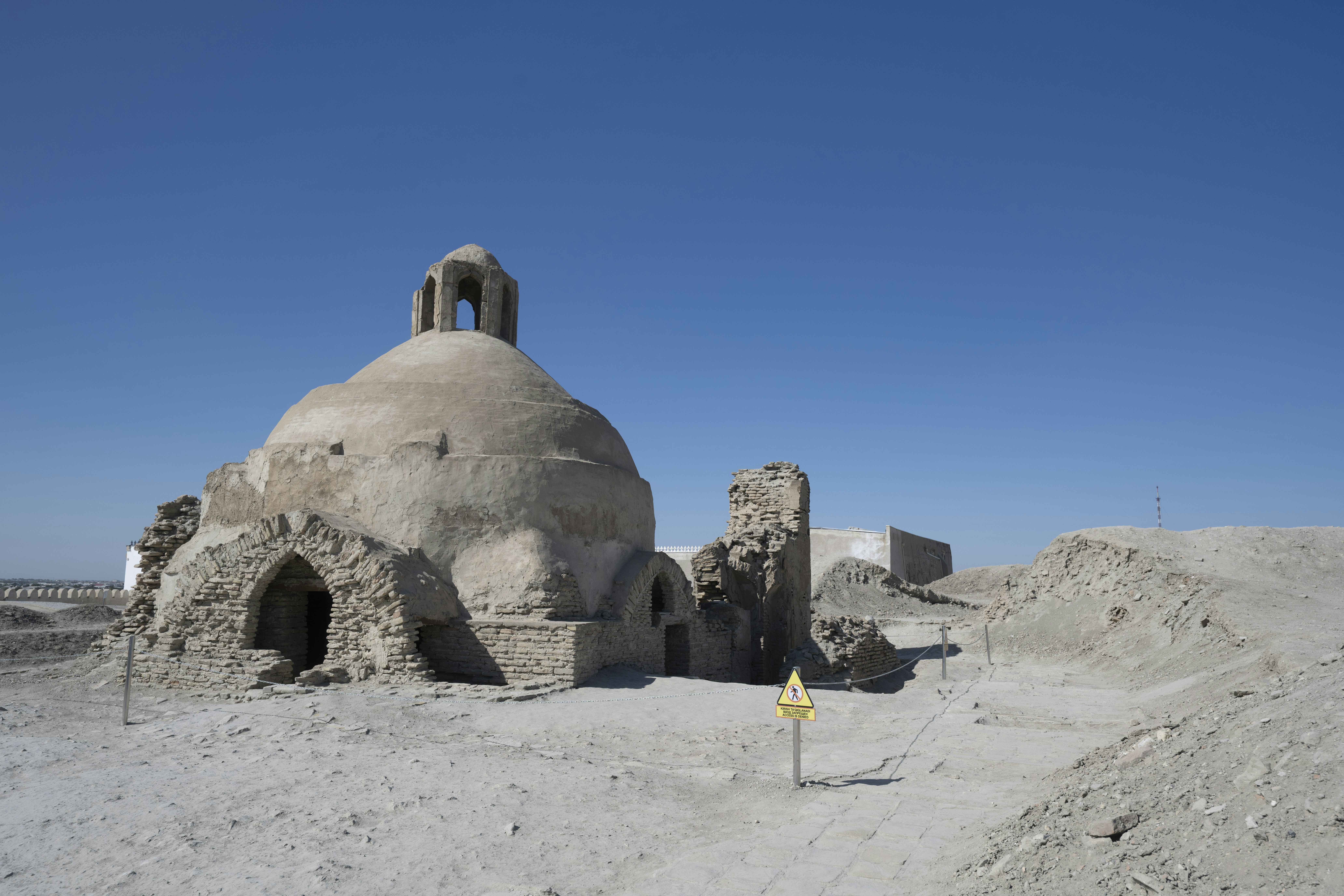 An ancient domed brick structure in a desert landscape under a clear blue sky