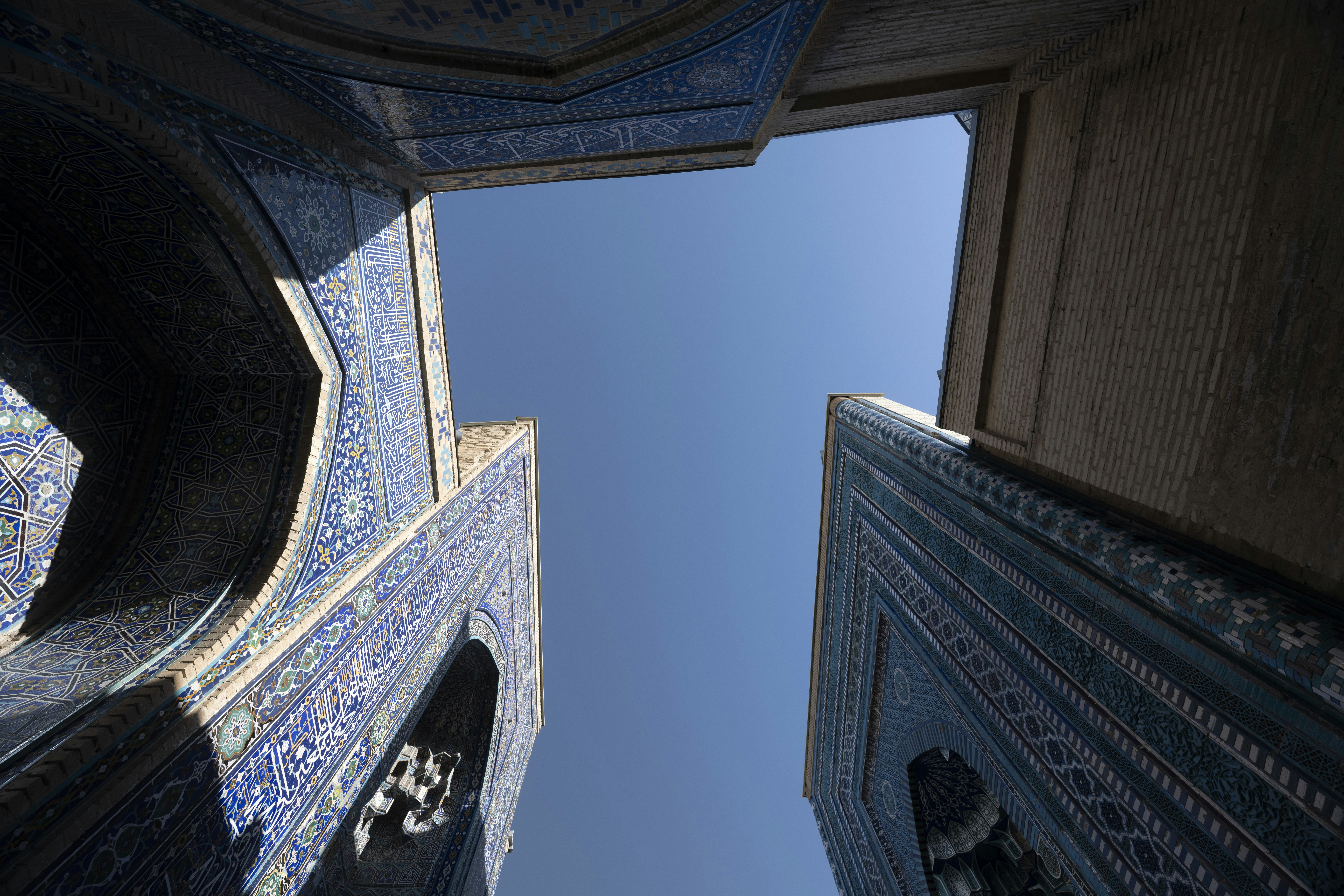 Low angle view of blue tiled archways framing a clear blue sky