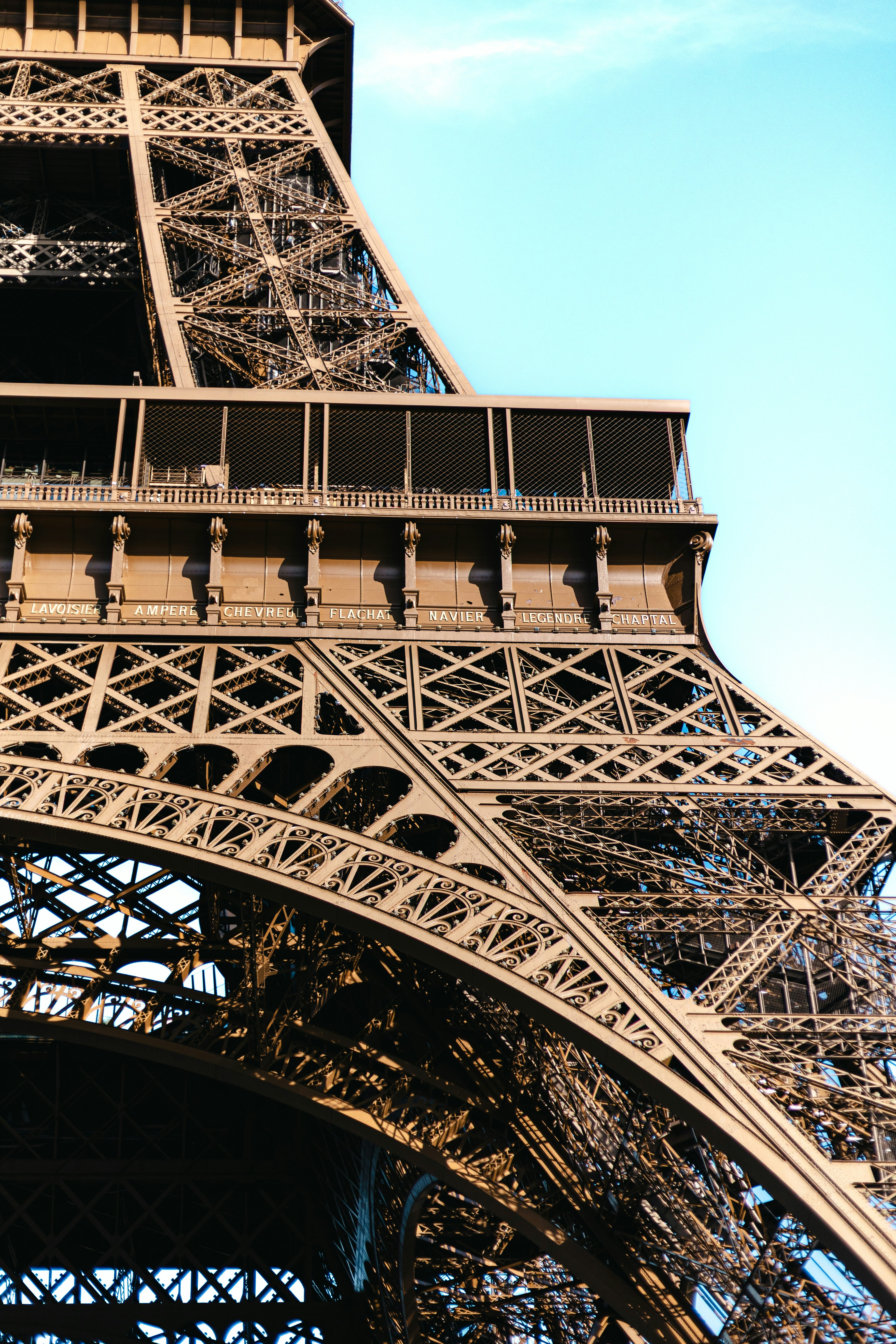 The iron lattice structure of the Eiffel Tower in Paris against a blue sky
