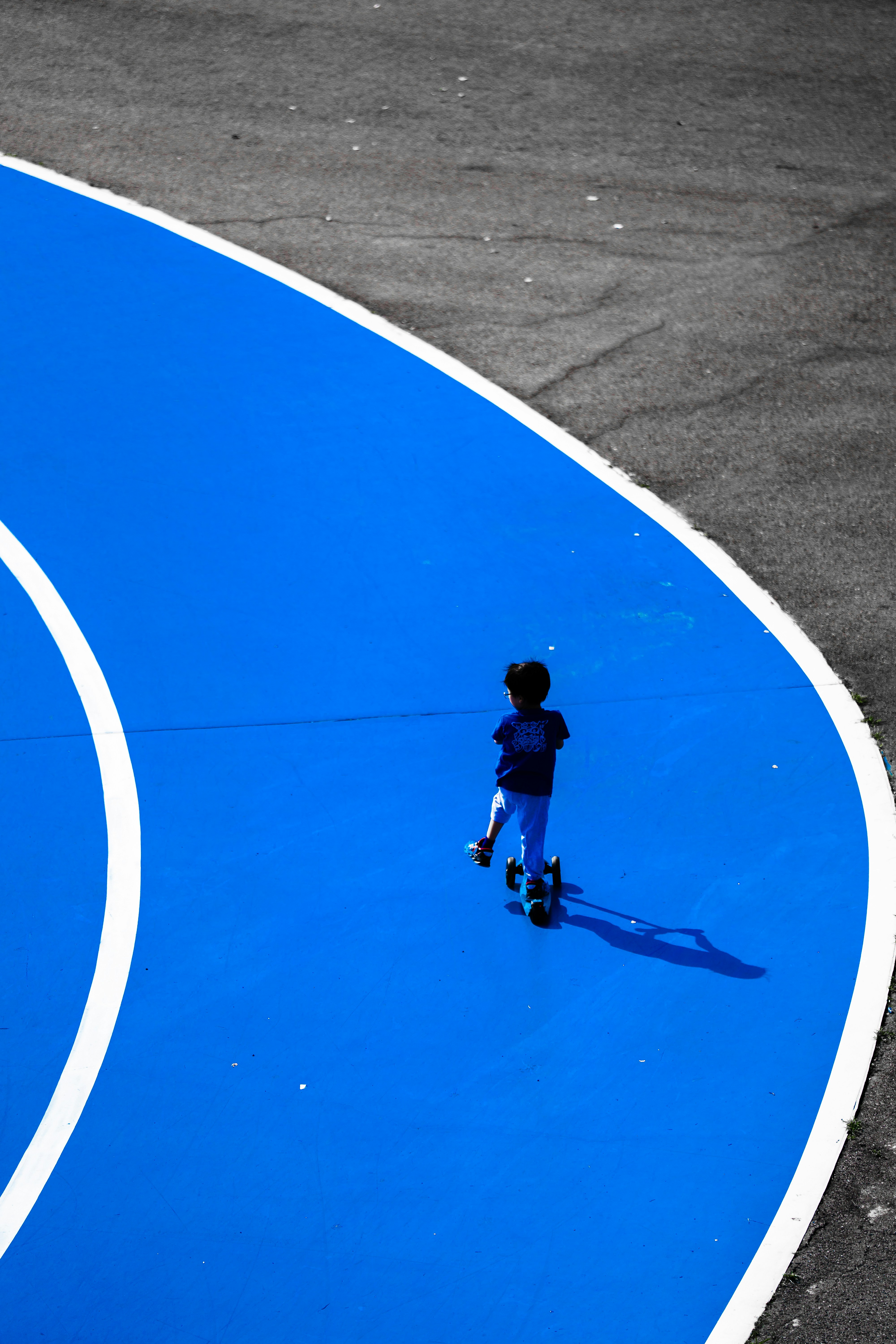 A child riding a scooter on a bright blue curved track