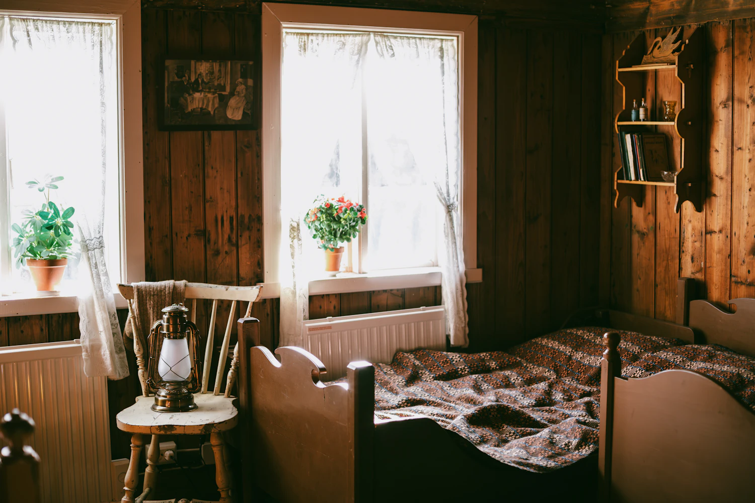 Timber-walled bedroom with a lantern on a wooden chair