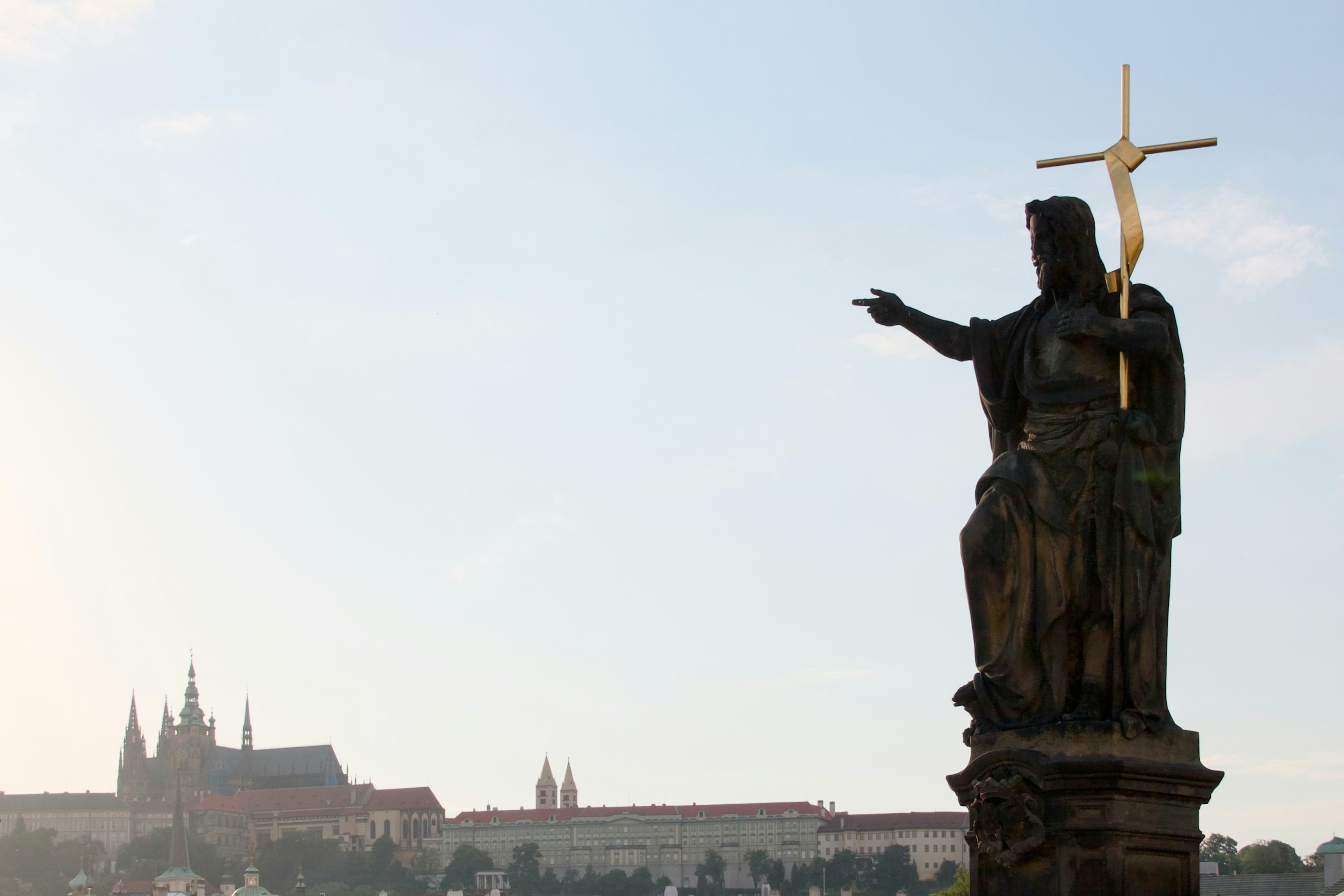 A bronze statue of a man holding a cross on Charles Bridge in Prague