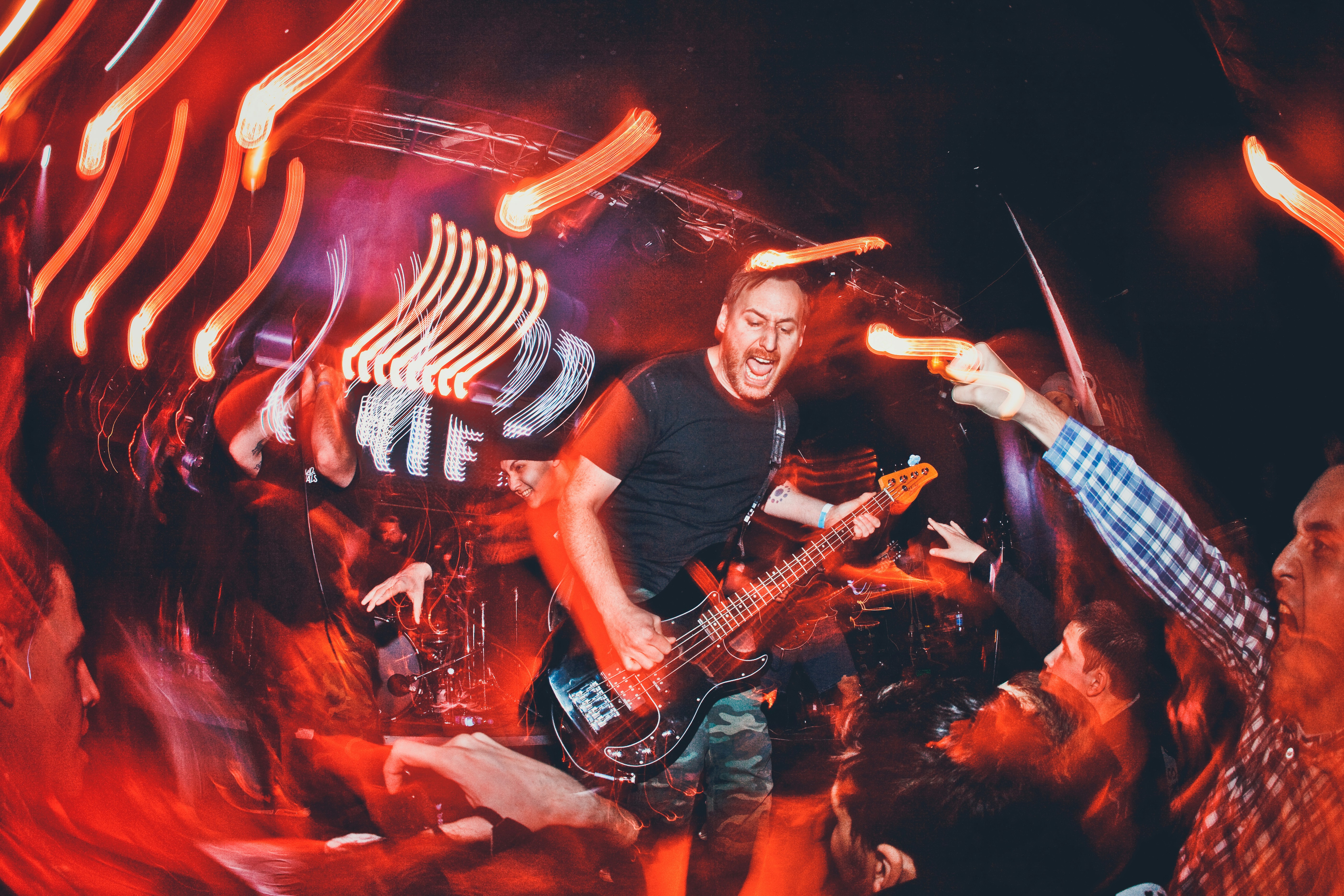Seorang pemain bass tampil di atas panggung dengan motion blur dan pencahayaan panggung merah