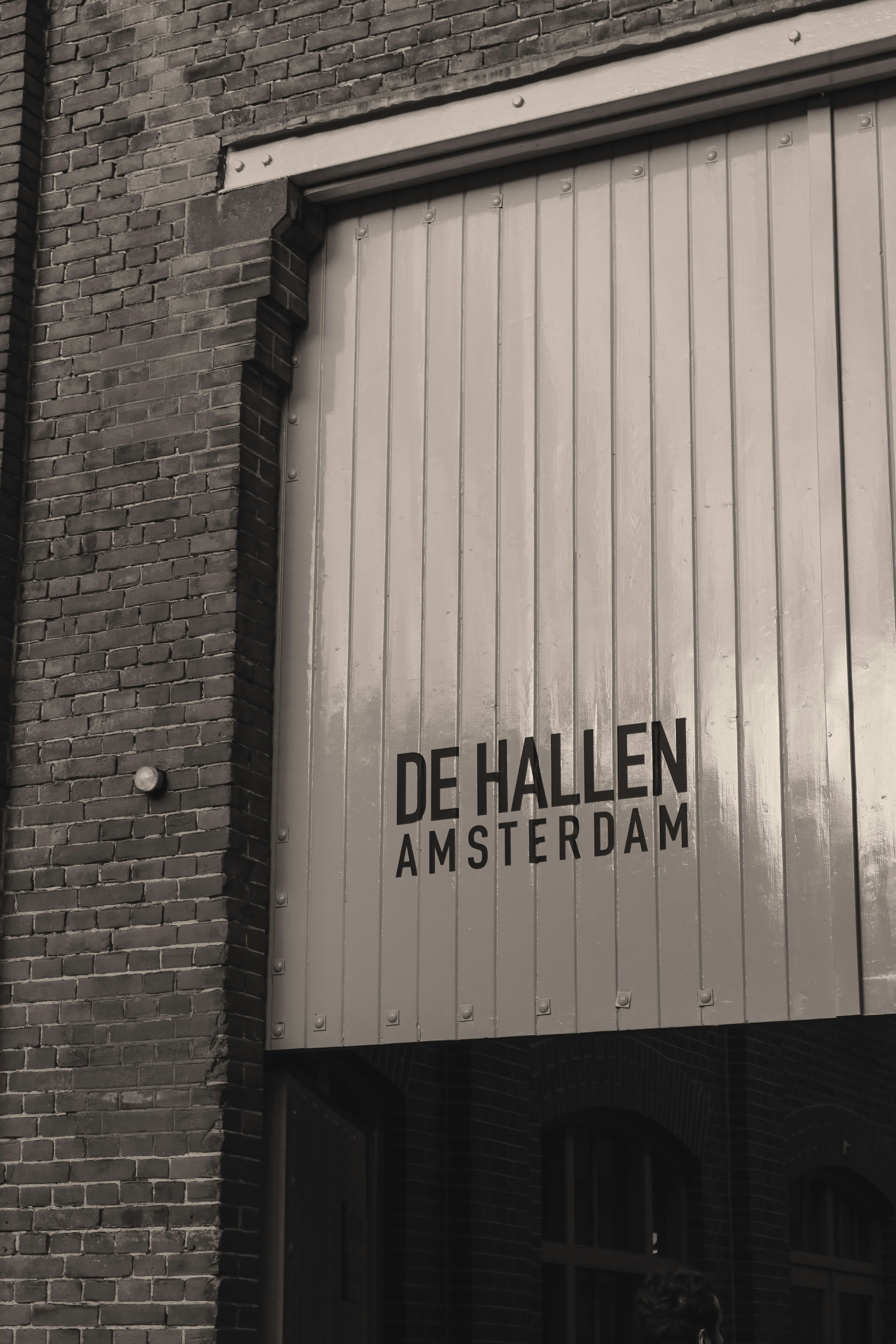 A large wooden door with the text De Hallen Amsterdam on a brick building