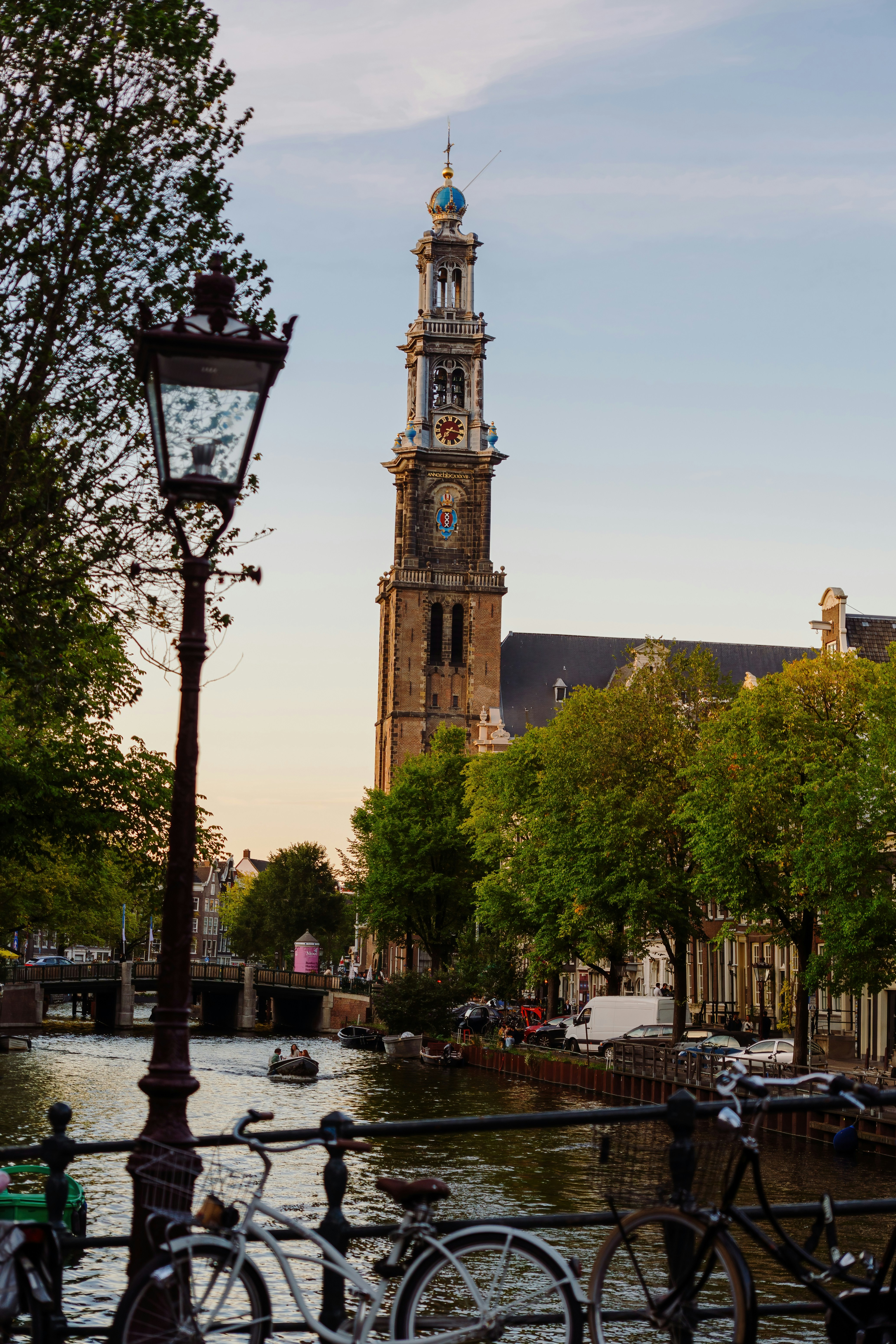 The Westerkerk tower rising above a canal with bicycles in Amsterdam