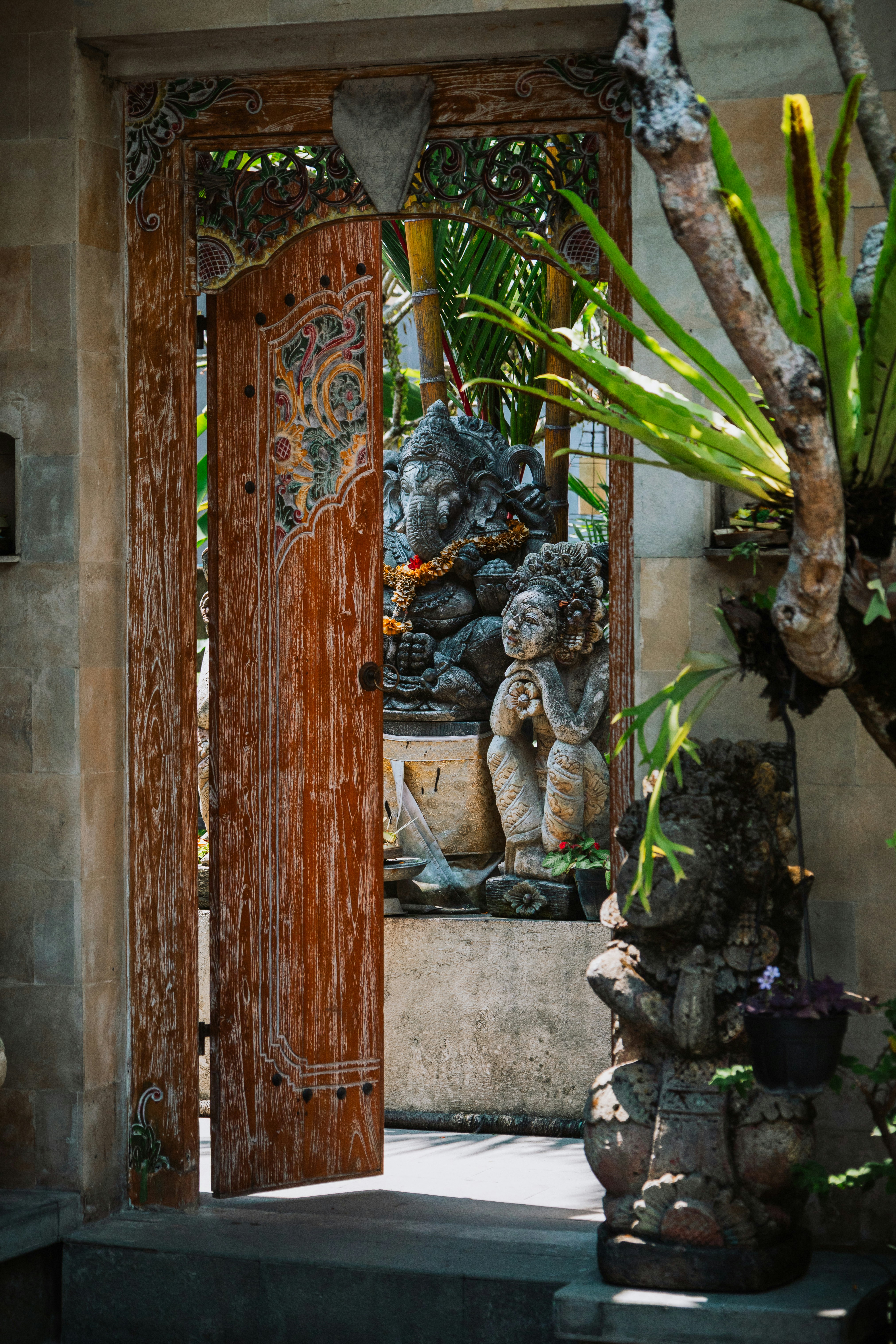 Stone Ganesha and a carved figure visible through an ornate wooden doorway