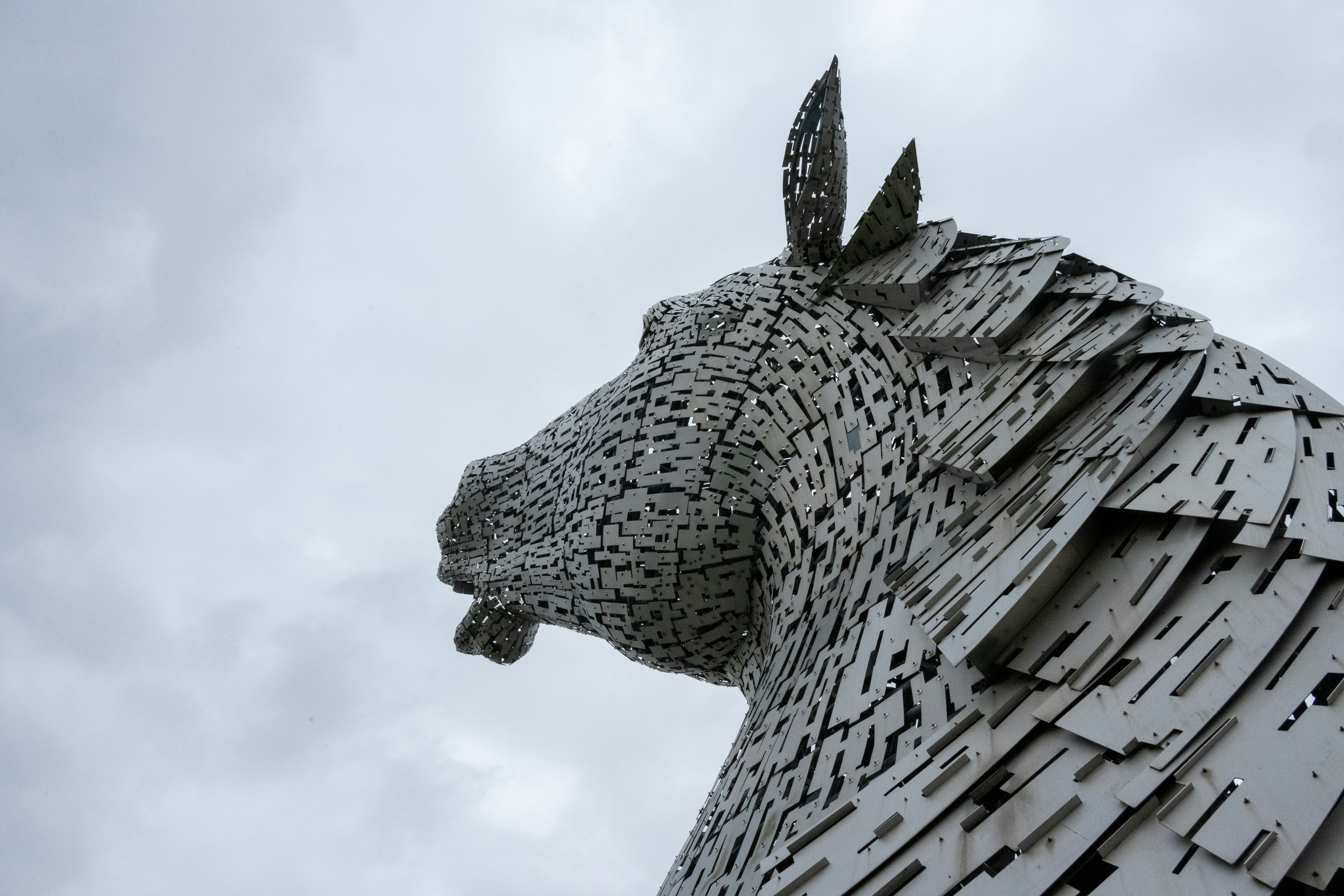 The Kelpies horse head sculpture made of metal plates against a cloudy sky