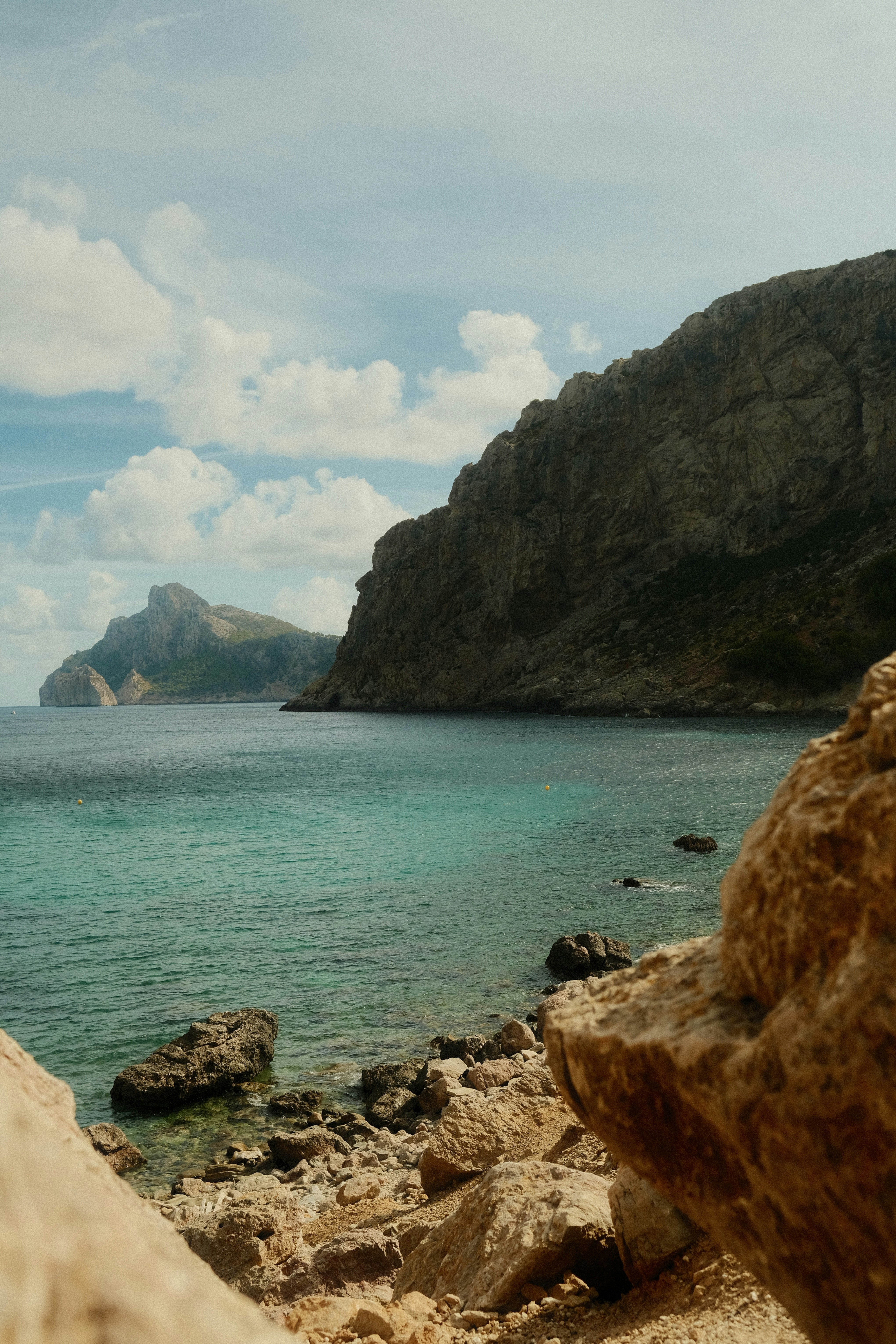 Turquoise water in a rocky bay with cliffs under a blue sky