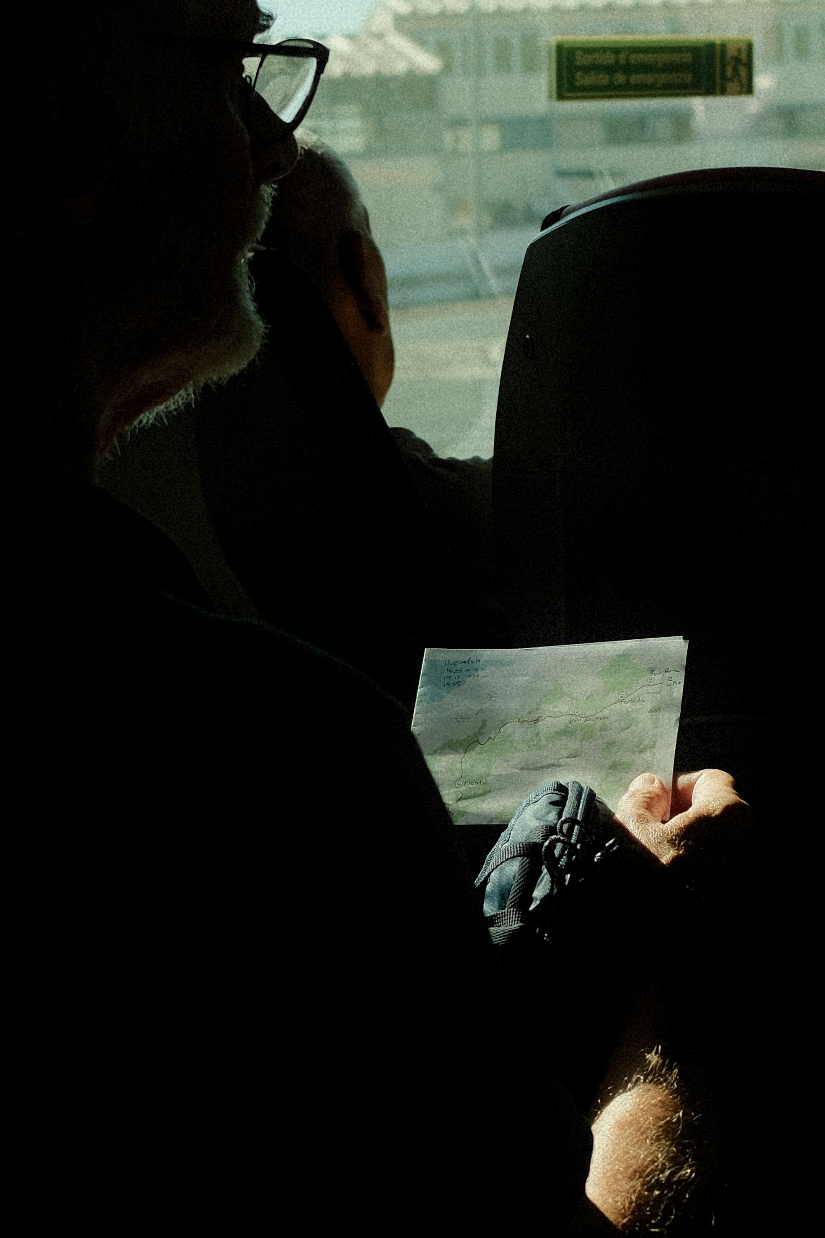A person in silhouette holding a small hand-drawn map on a bus
